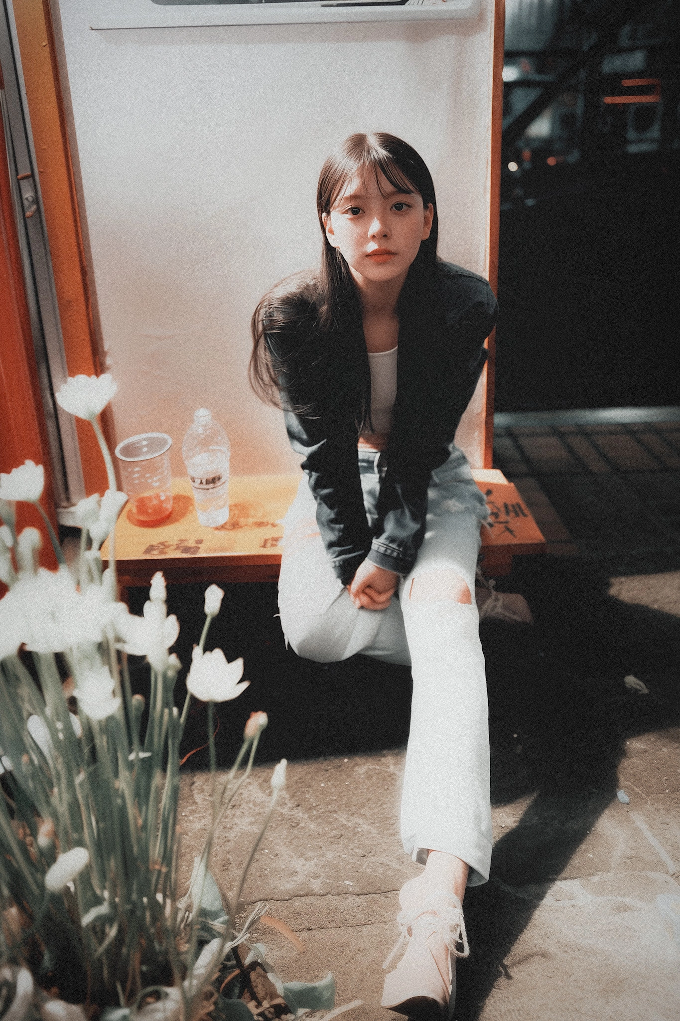 女人坐在一个凳子上,一瓶水和一杯茶。