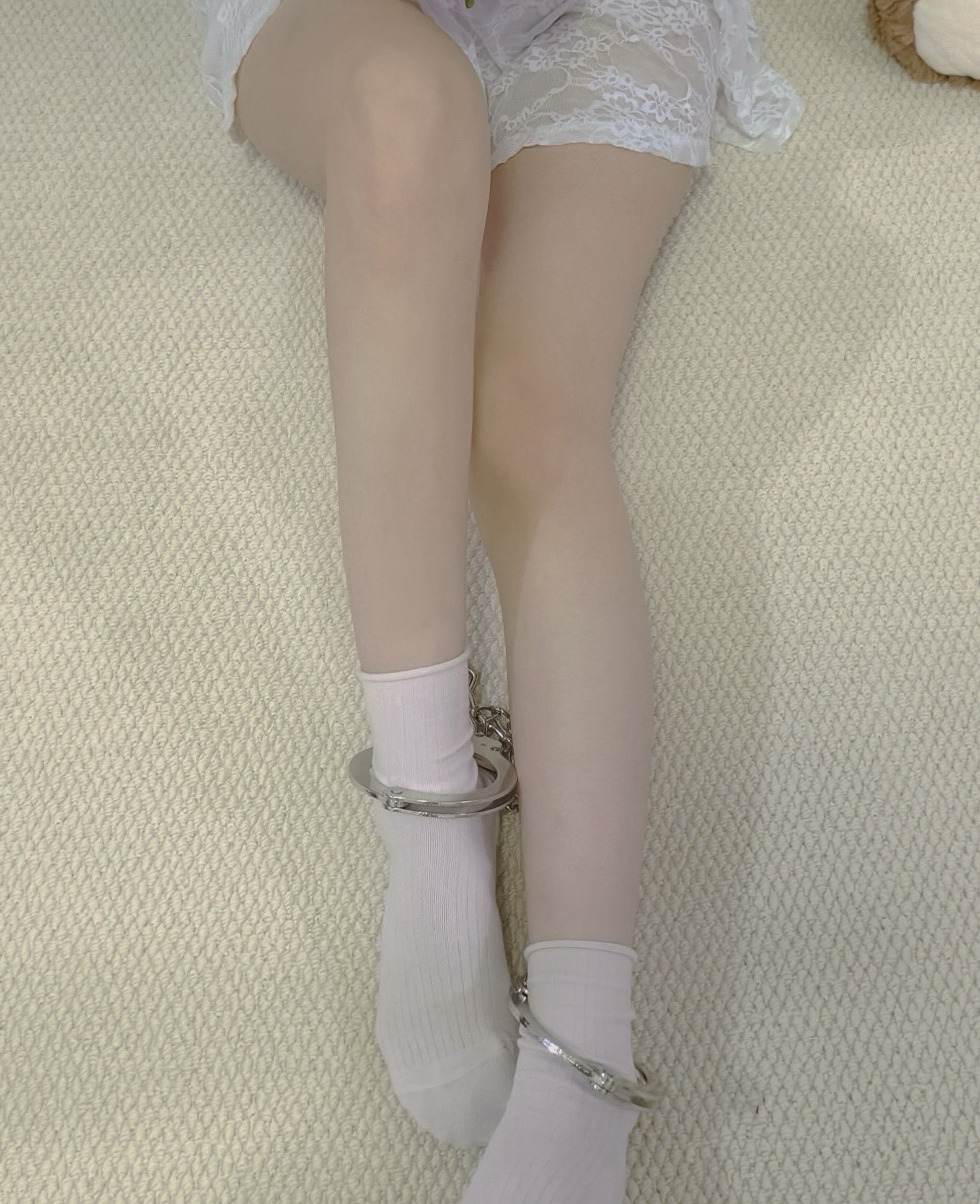 女人穿着一双白色袜子和一个银链围绕她的脚踝。