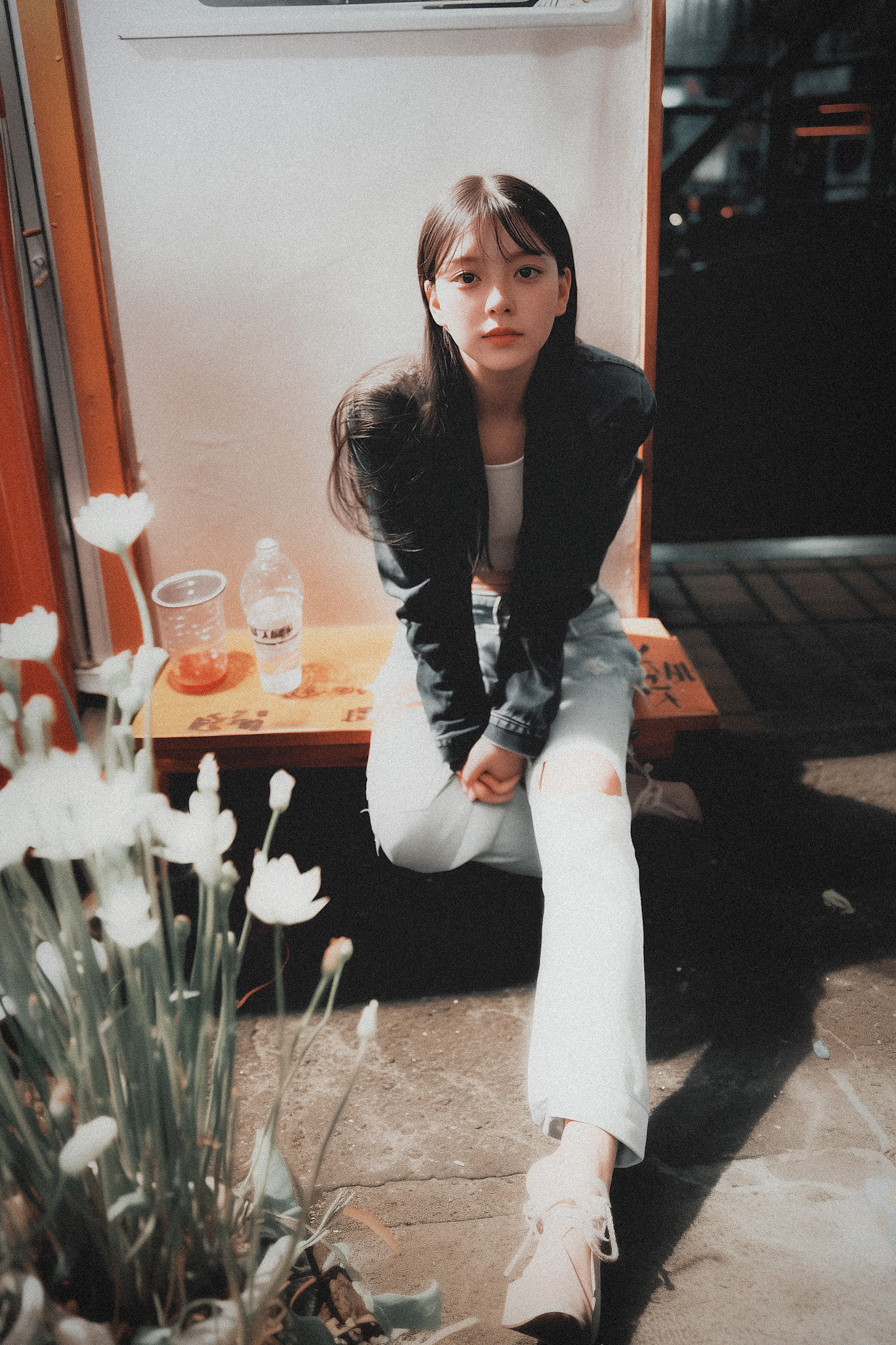 女人坐在一个凳子上,一瓶水和一杯茶。