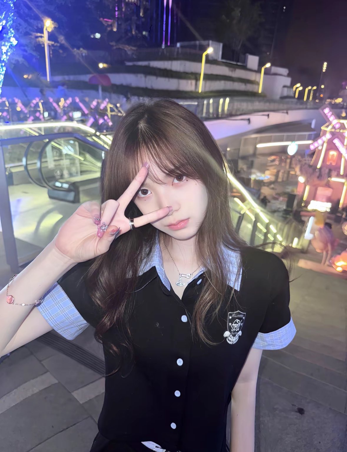 一位穿着黑色衬衫和蓝色的袖子的女人正在做和平的信号。