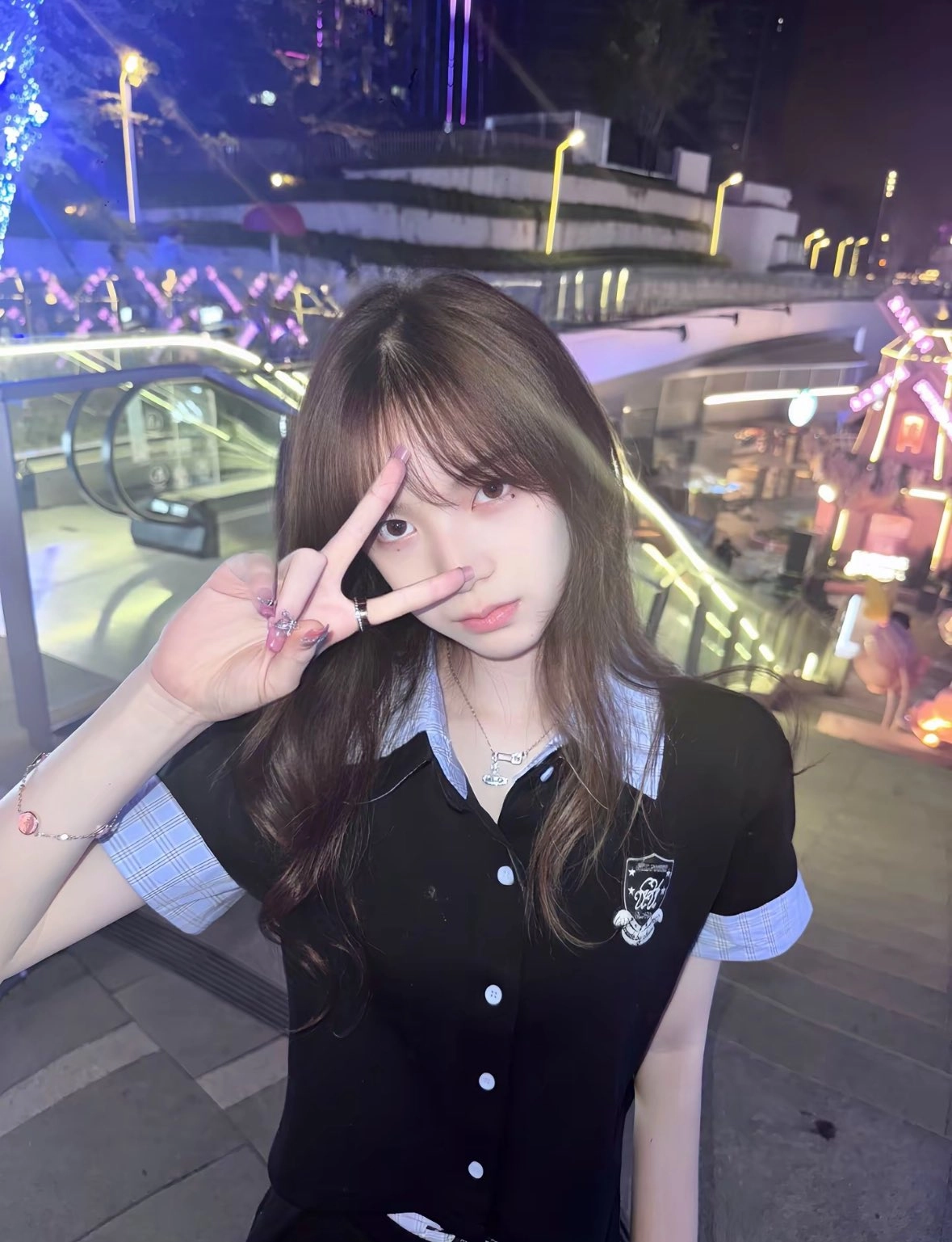 一位穿着黑色衬衫和蓝色的袖子的女人正在做和平的信号。