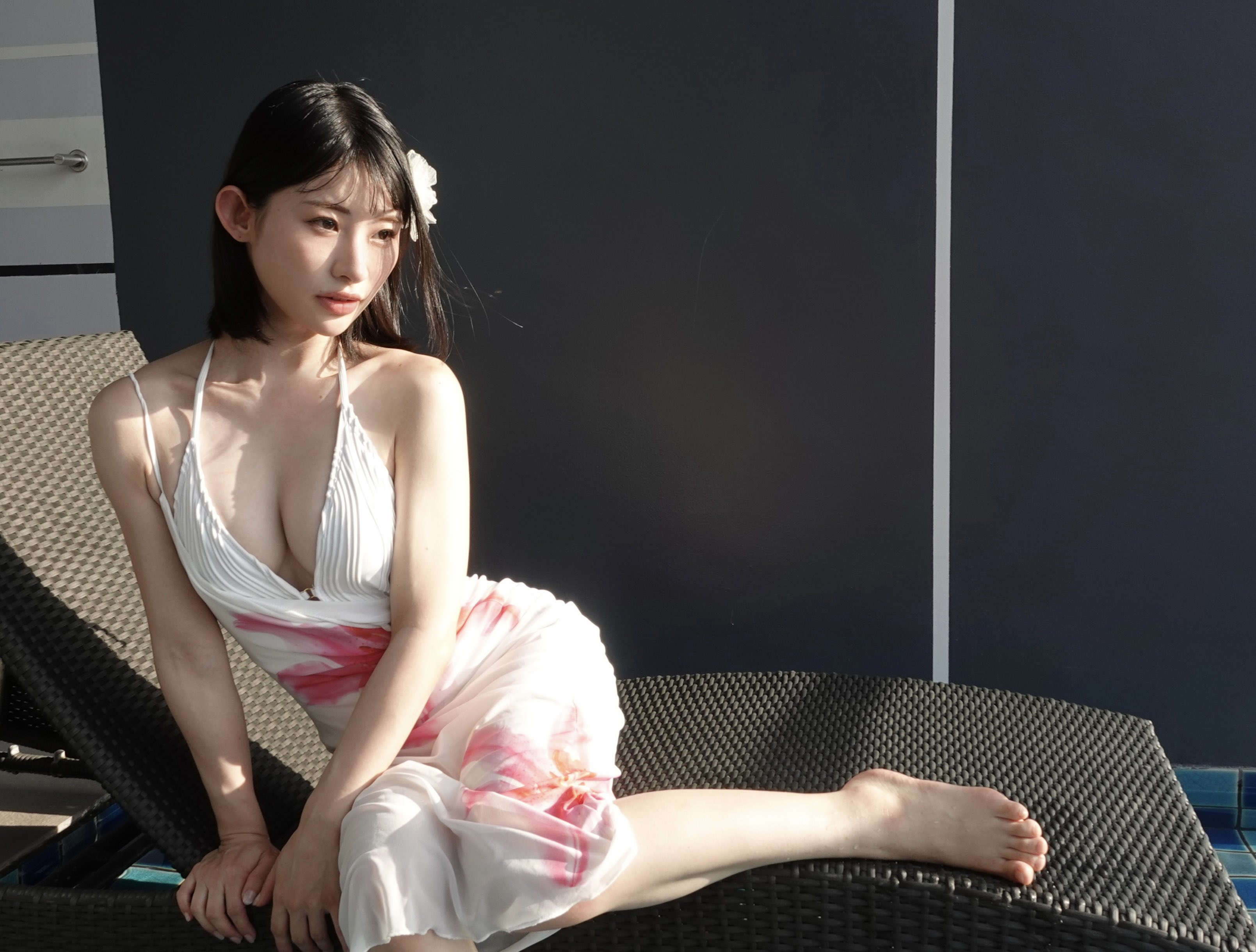 一位穿着白色裙子的女人,头发里有一朵花,坐在织布的椅子上。