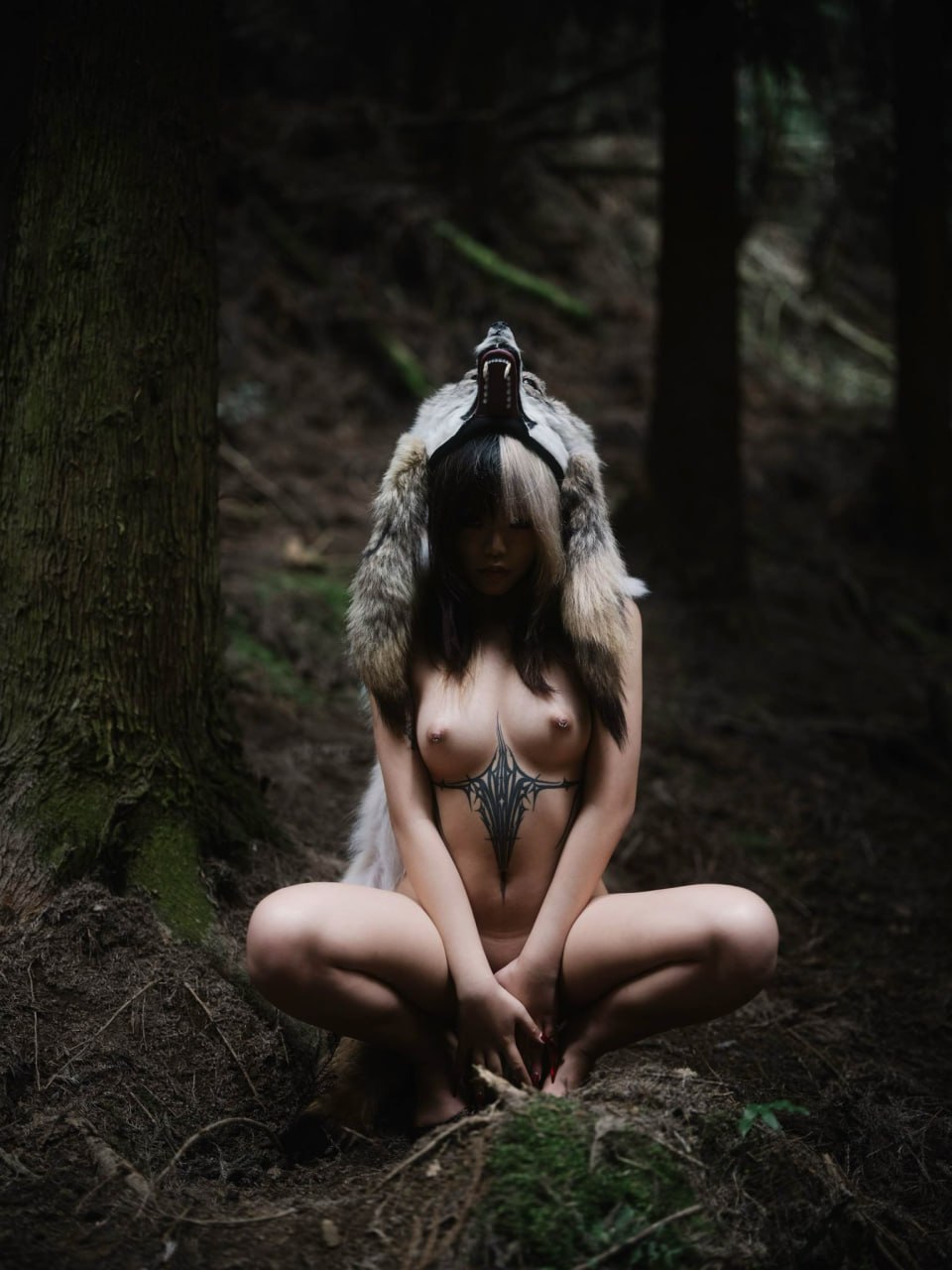 戴着狼帽的女人坐在树林里。