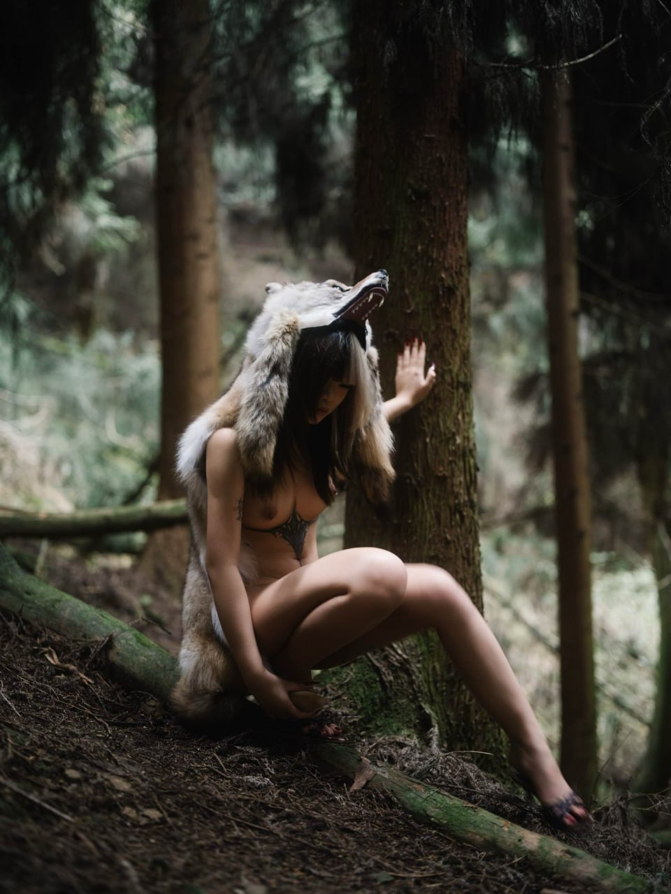 戴着狼帽的女人坐在树林里。