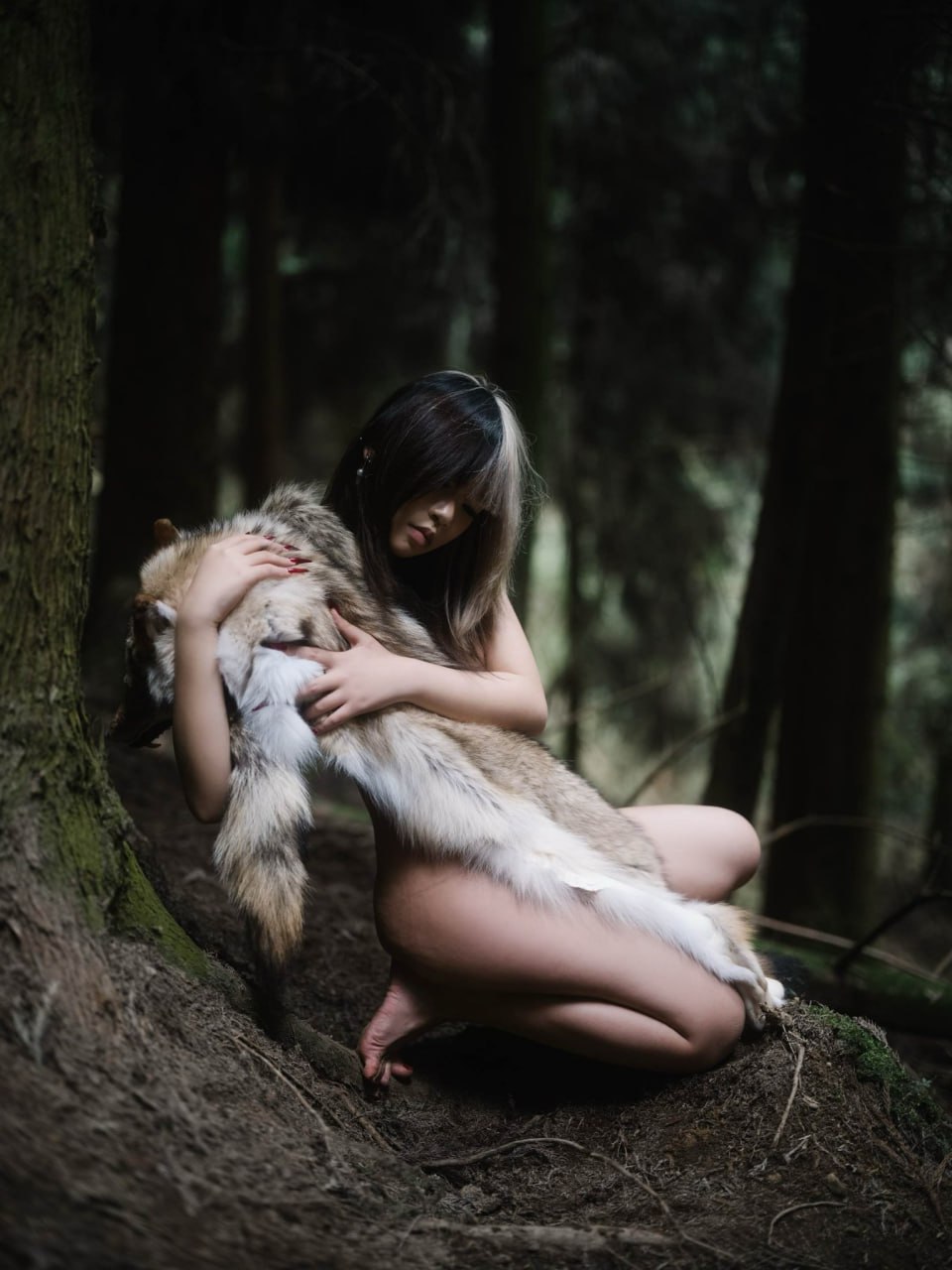 戴着狼帽的女人坐在树林里。