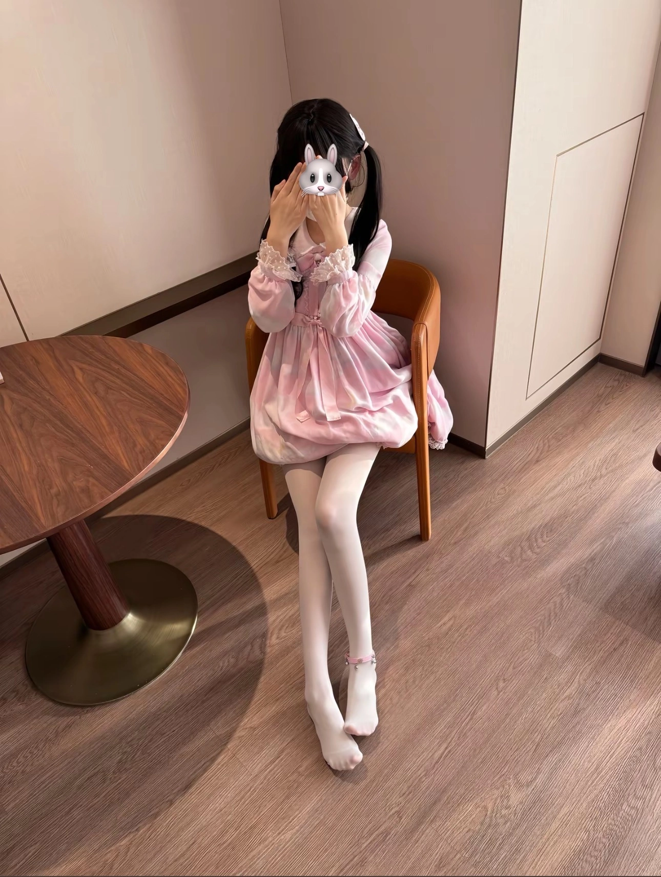 一位穿着粉红色的裙子和白色袜子的女孩坐在椅子上。