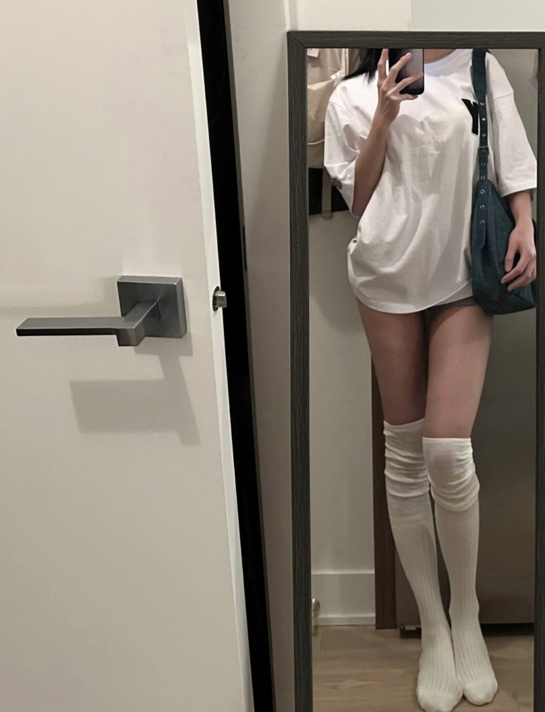 一位穿着白色衬衫和蓝色牛仔裤的女人站在镜子前。