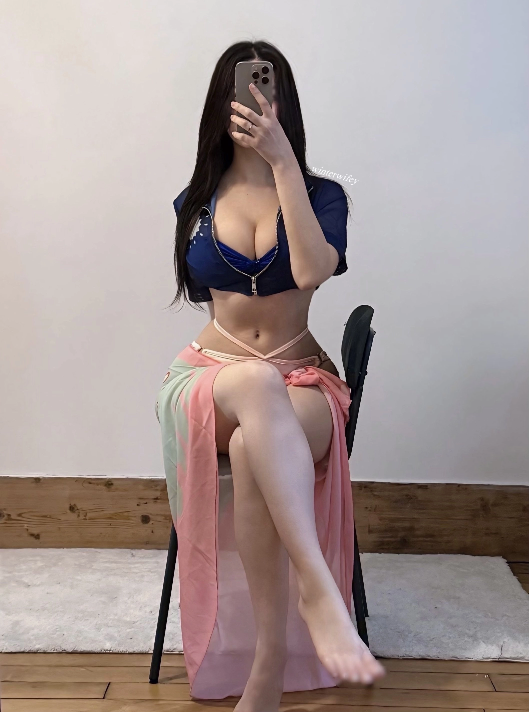 一位穿着蓝色衬衫和粉红色裙子的女人坐在椅子上。