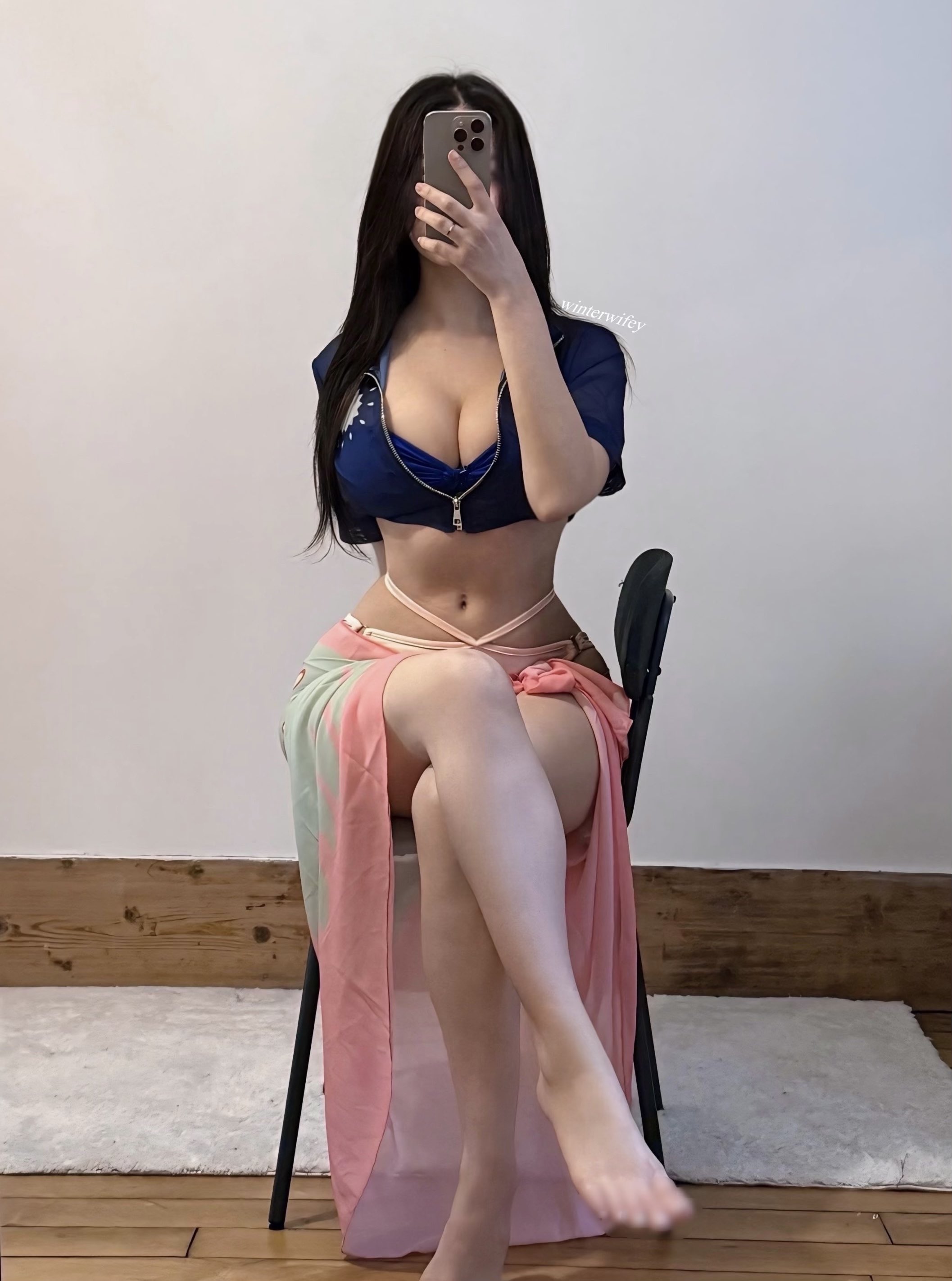 一位穿着蓝色衬衫和粉红色裙子的女人坐在椅子上。