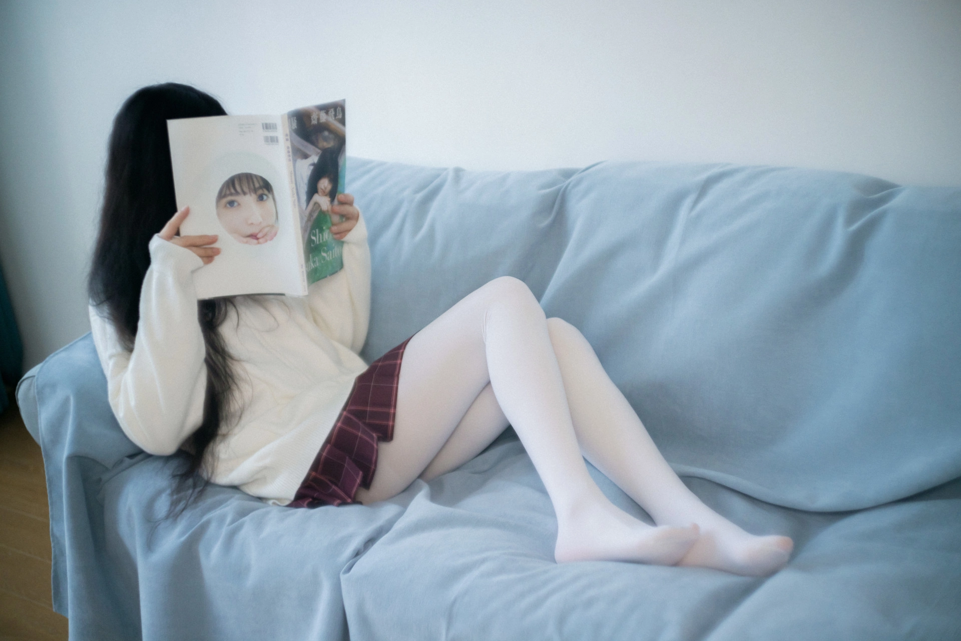 女人坐在沙发上读杂志。