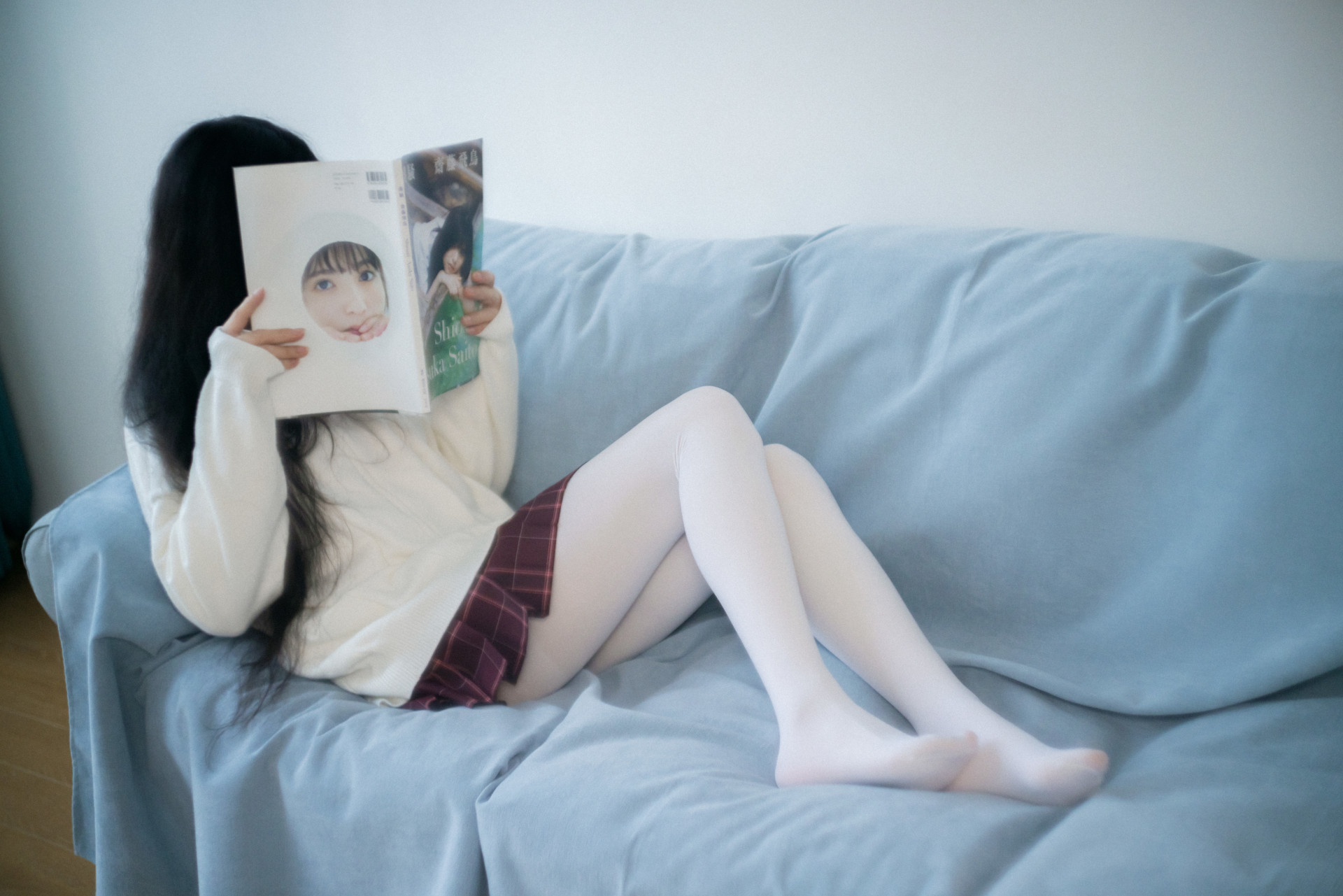 女人坐在沙发上读杂志。