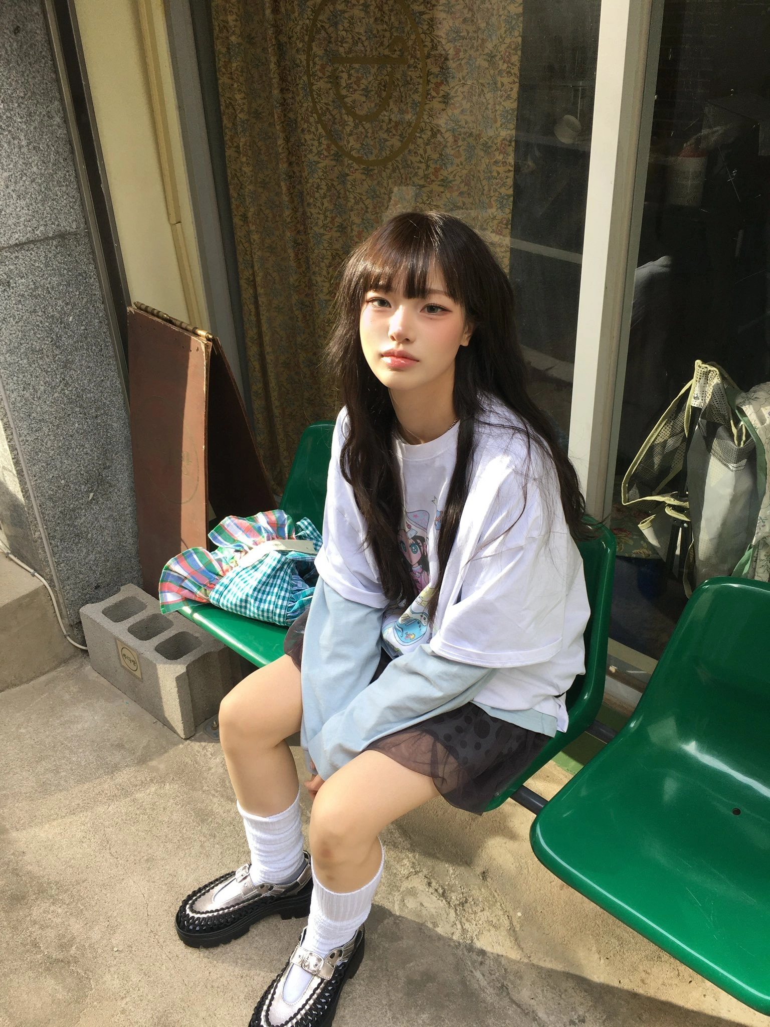 女孩坐在绿色的凳子上。