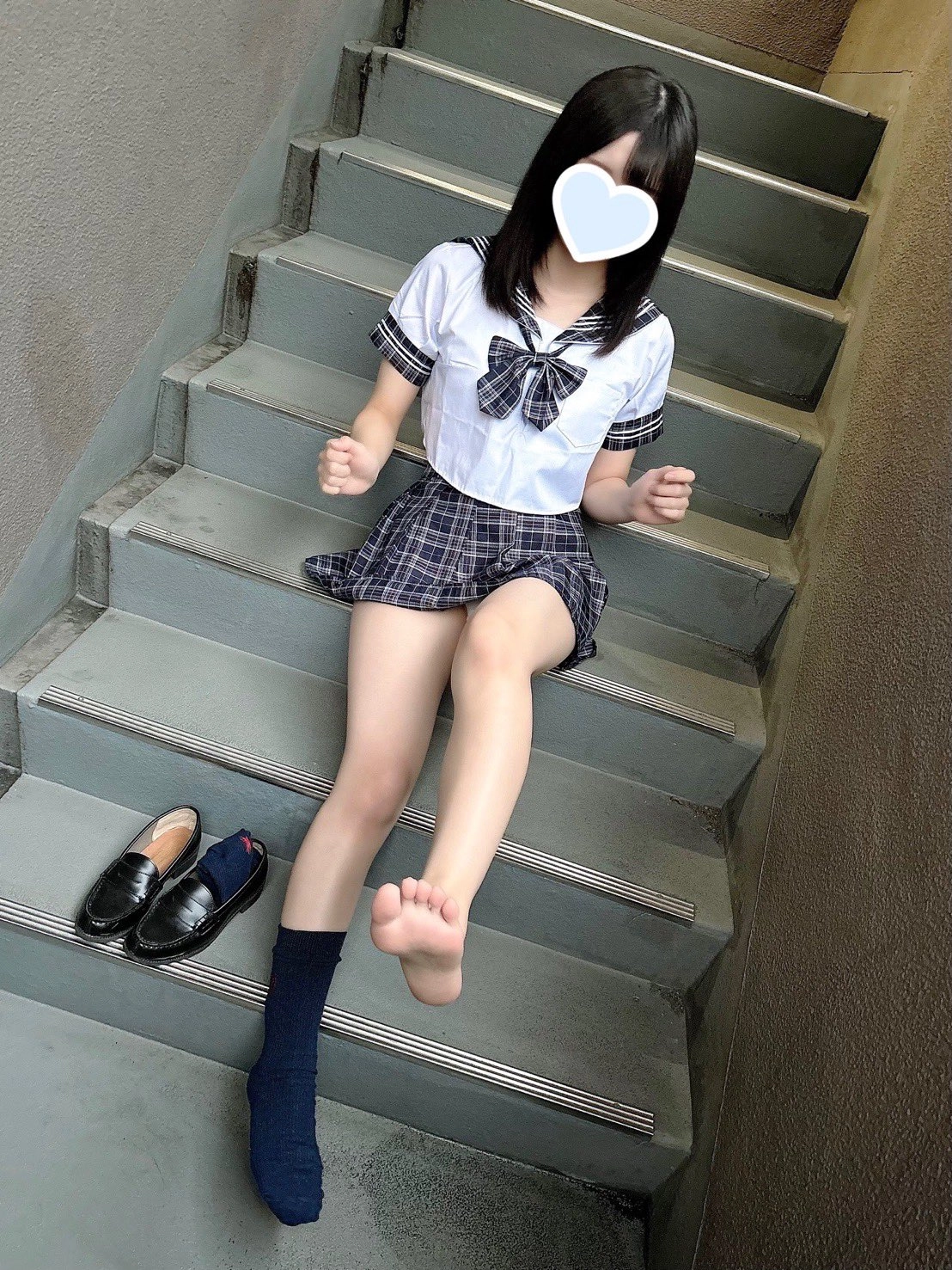 穿着白色衬衫和蓝色裙子的女孩坐在楼梯上。