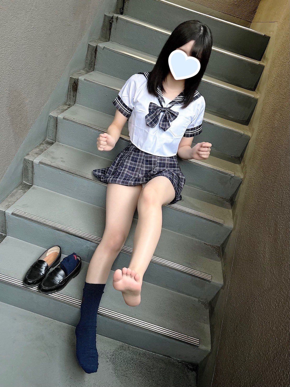 穿着白色衬衫和蓝色裙子的女孩坐在楼梯上。