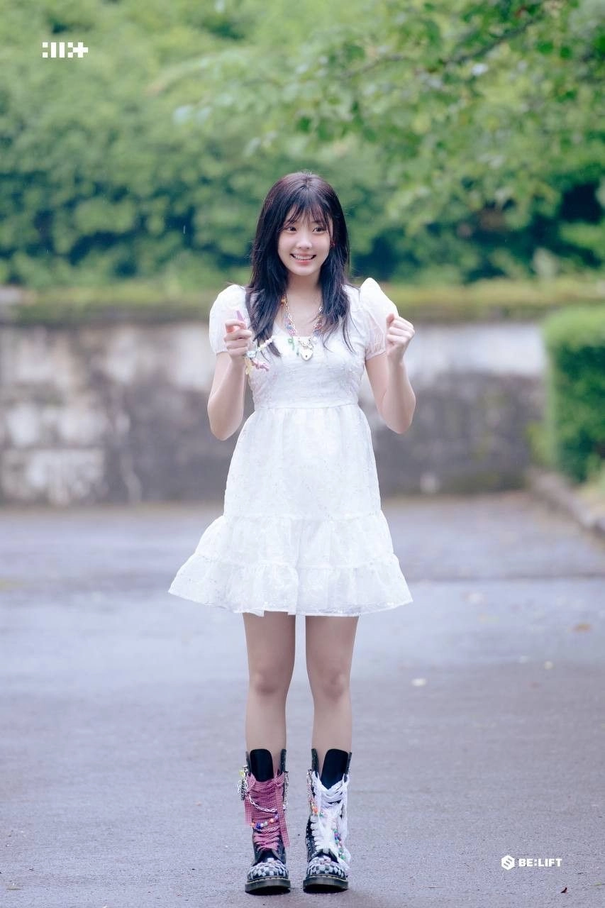 一位穿着白色裙子和靴子的女人拿着手机。