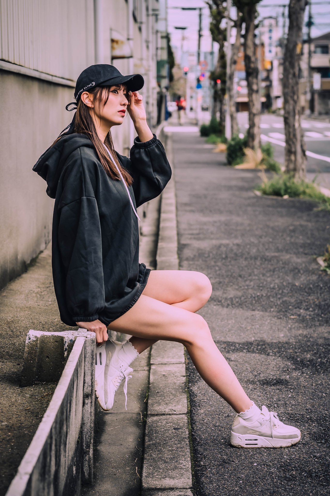 穿着黑色帽子和白色鞋子的女人坐在一个边缘。