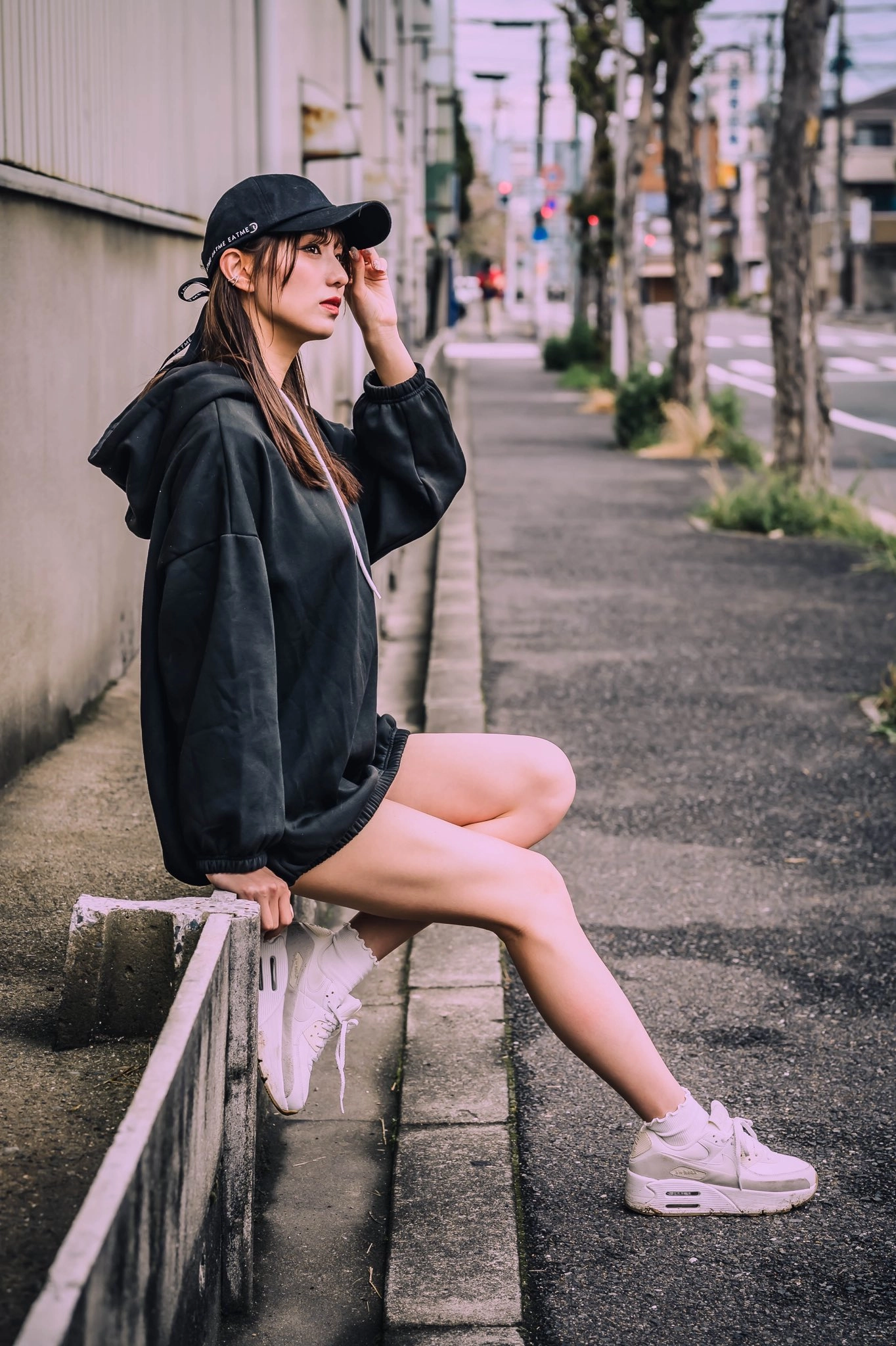 穿着黑色帽子和白色鞋子的女人坐在一个边缘。