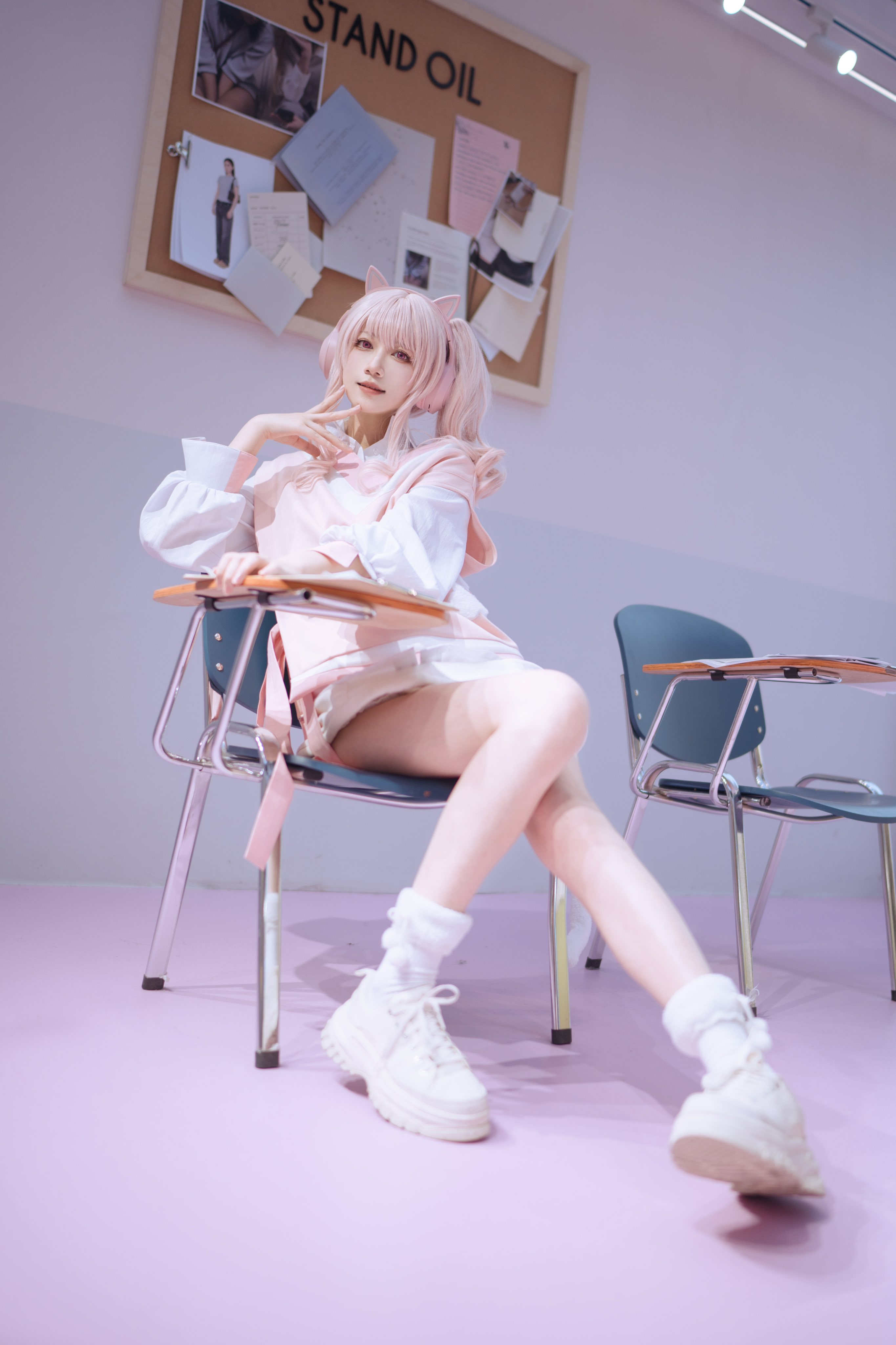 女孩站在一个椅子上,穿着粉红色的夹克和白色的鞋子。