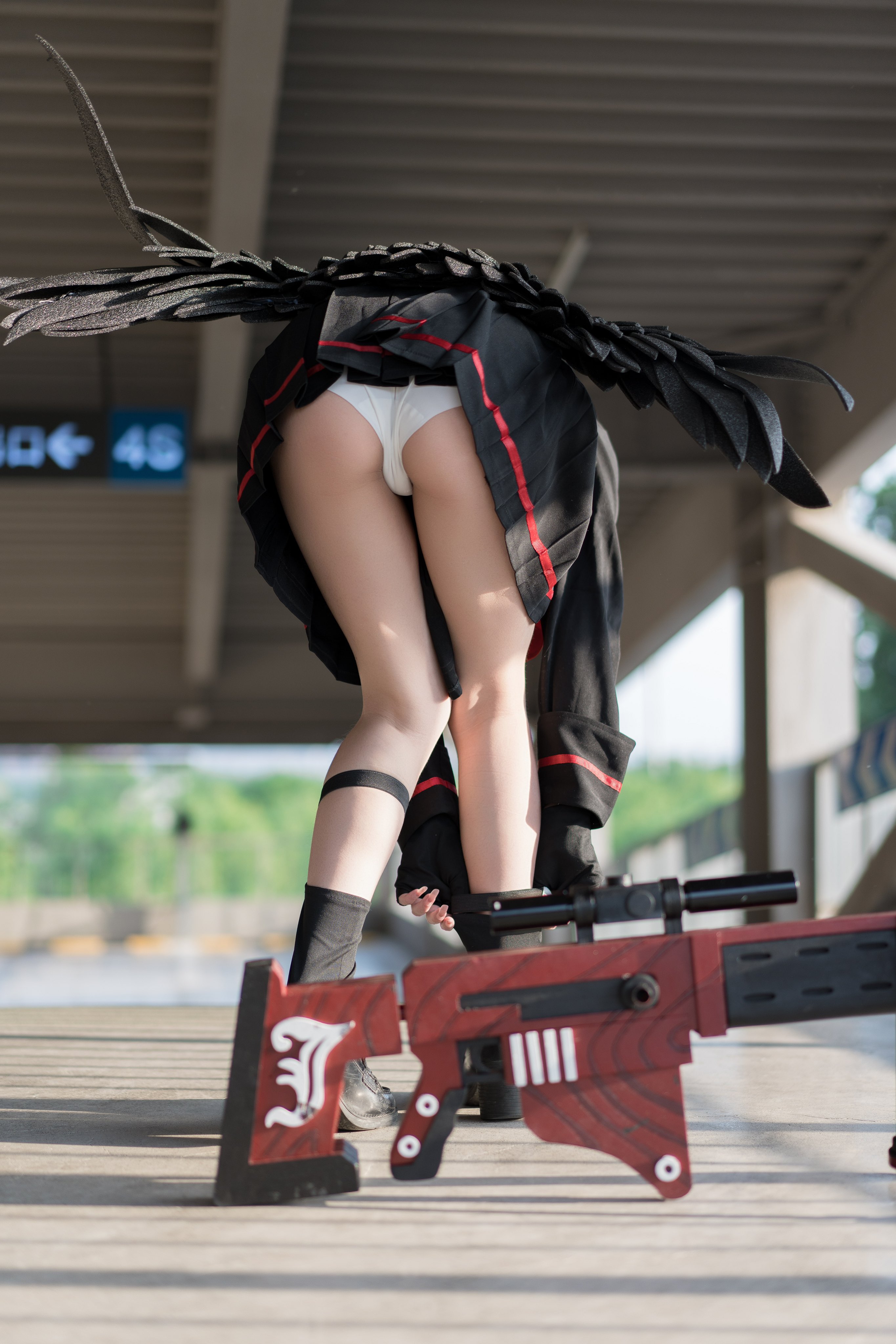 一位穿着黑色和红色的衣服和黑色的翅膀的女人走在一座桥上。