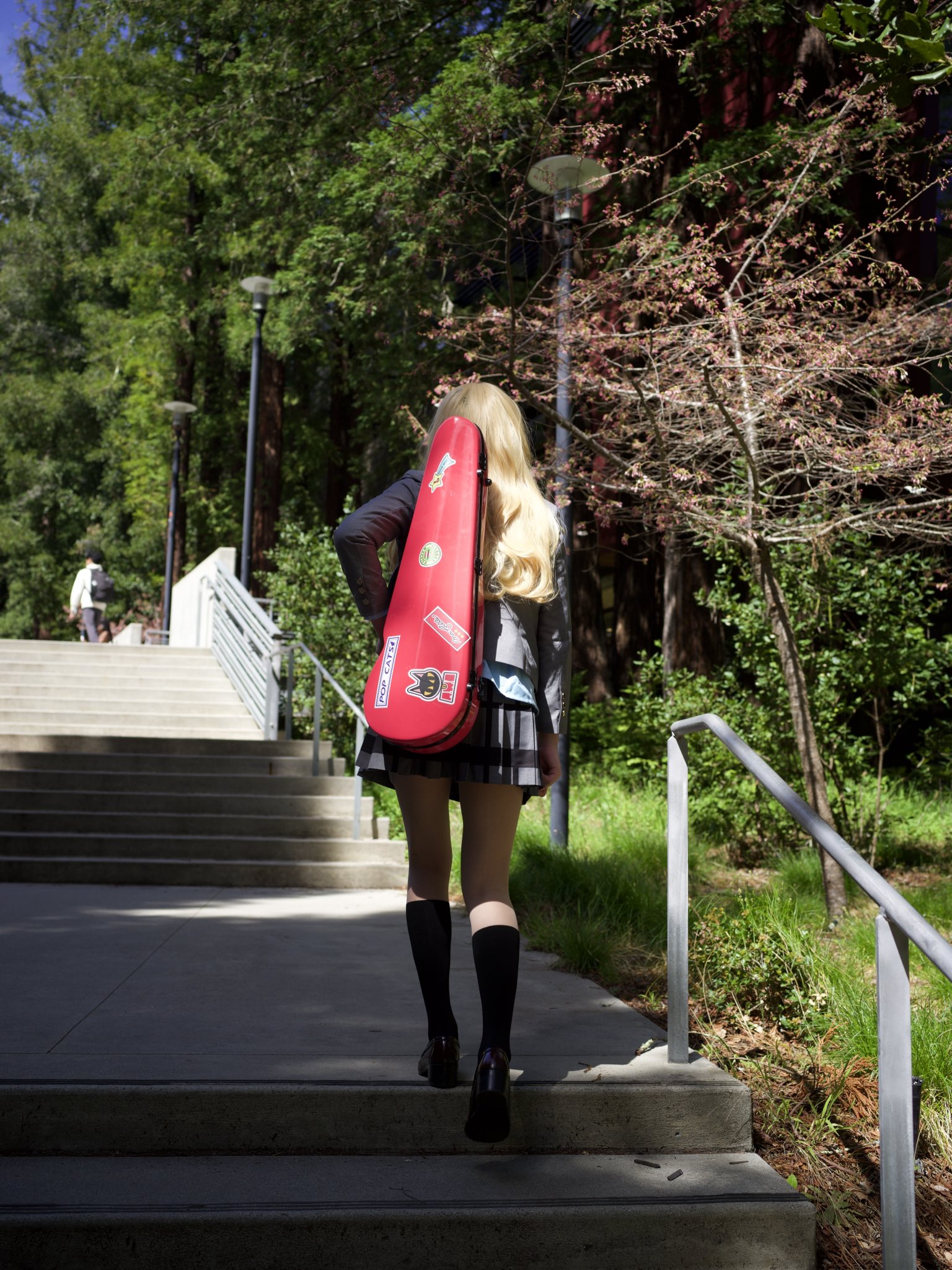 一位带着红色吉他盒子的女人走下了一段楼梯。