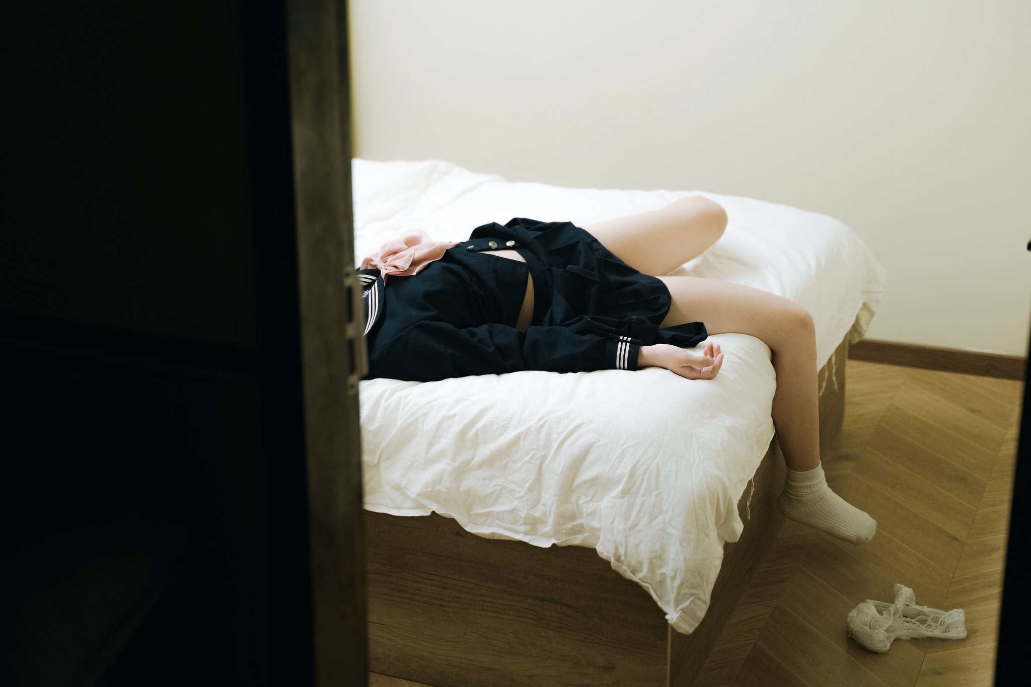 一位穿着黑色衬衫和黑色裙子的女人躺在床上。