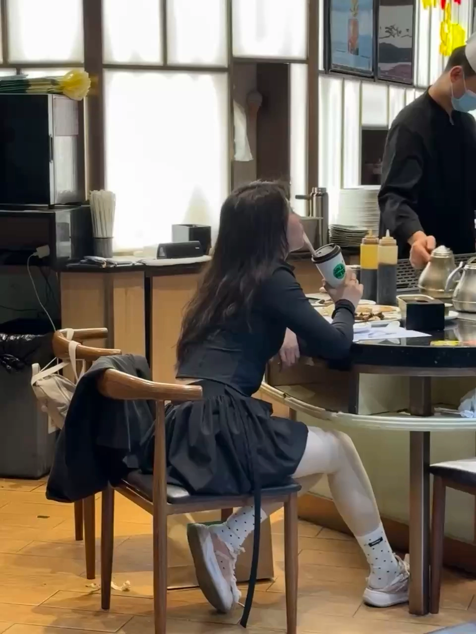 穿黑衣的女人喝咖啡。