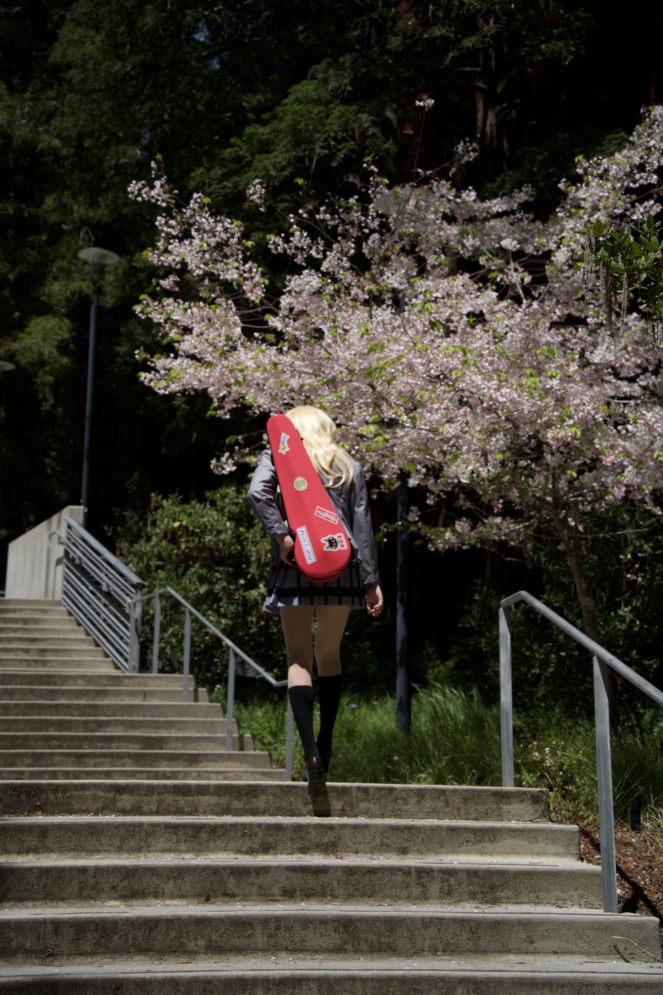 一位带着红色吉他盒子的女人走下了一段楼梯。