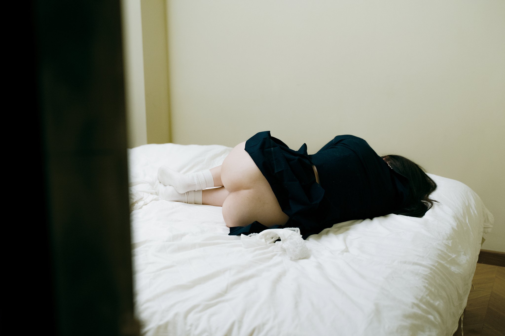 一位穿着黑色衬衫和黑色裙子的女人躺在床上。