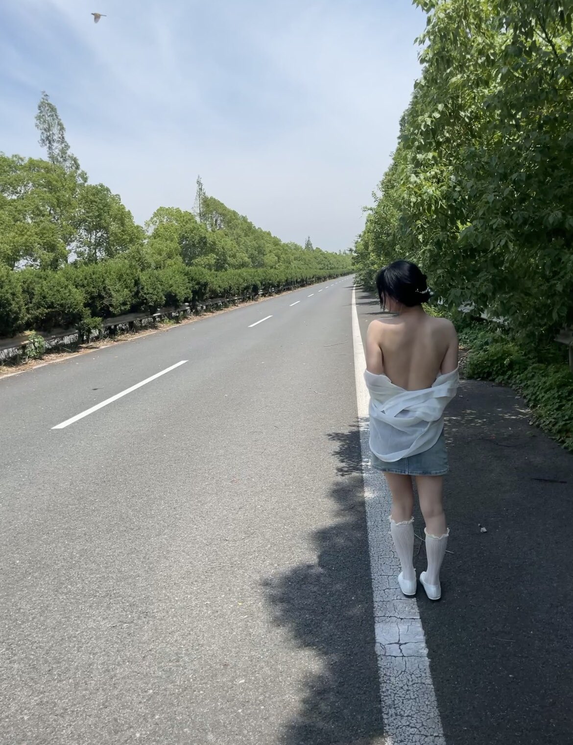 一位穿着白色衬衫和白色袜子的女人走在街上。