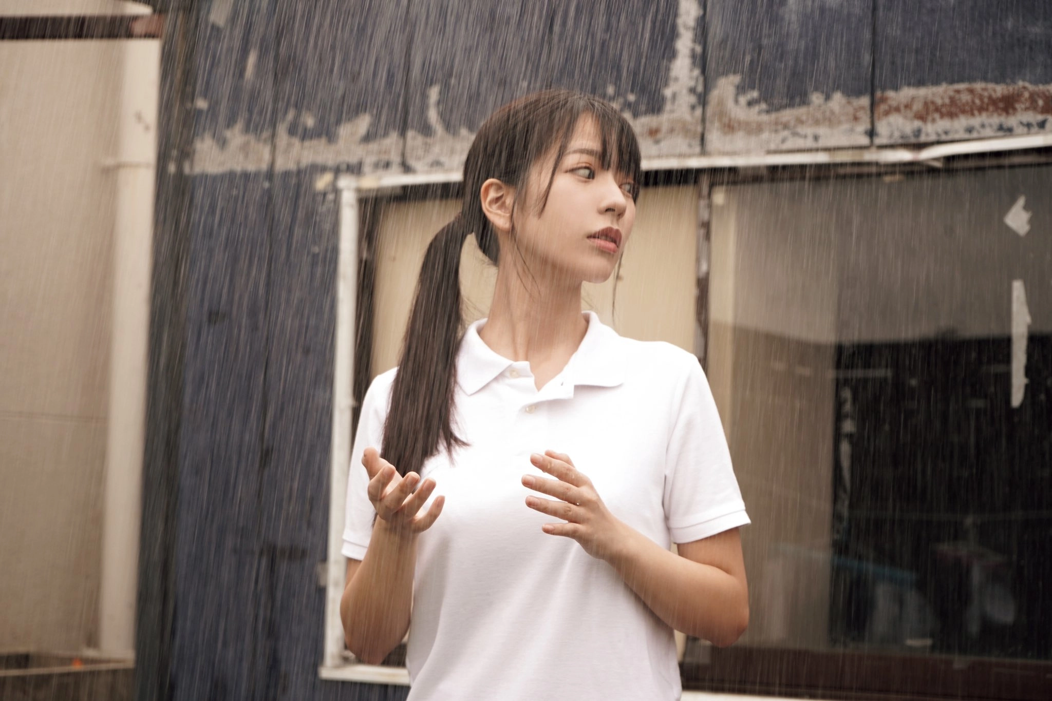 女孩带着一只马尾巴和一件白色衬衫站在雨中。