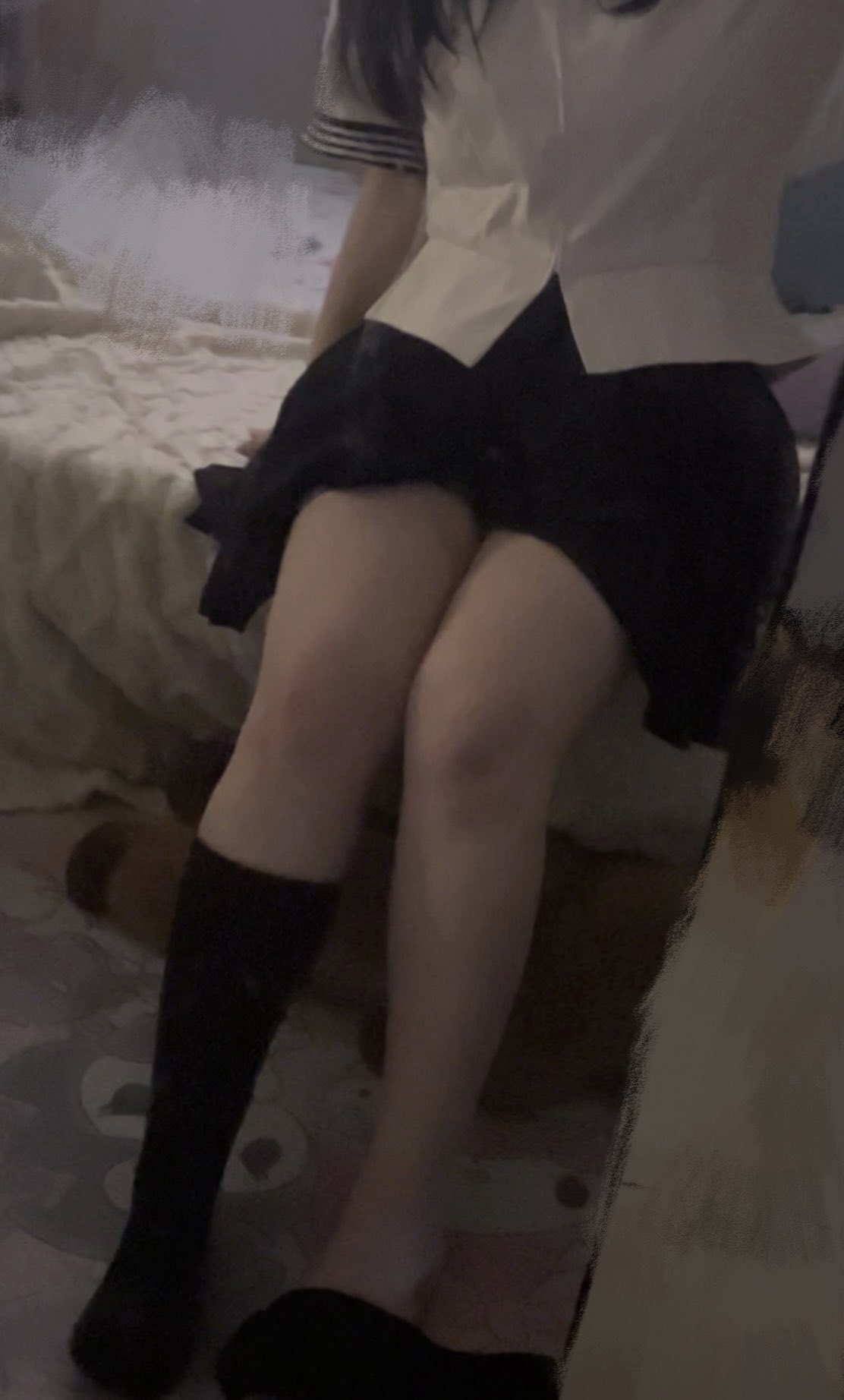 一位穿着白色衬衫和黑色衬衫的女人坐在床上。