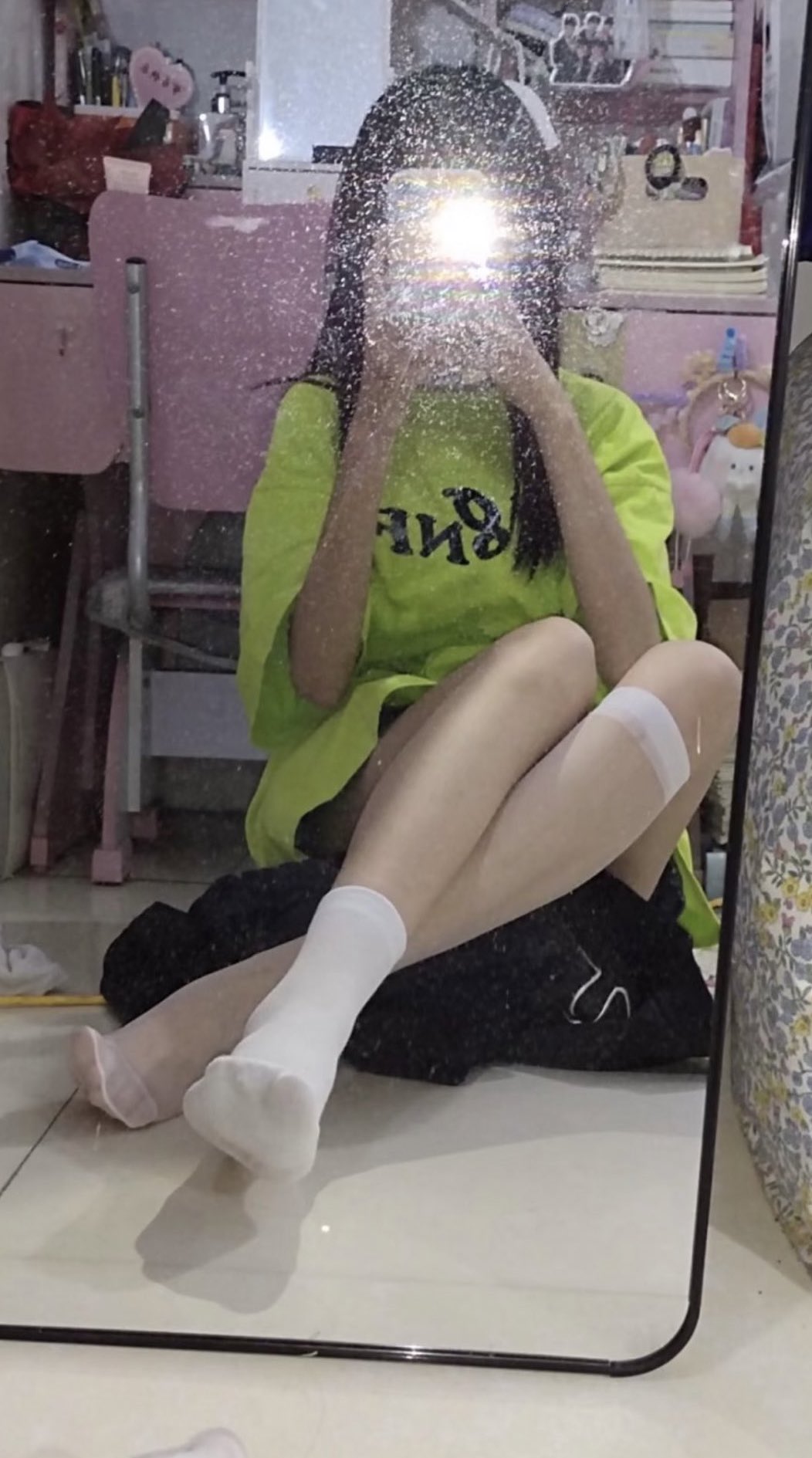 一位穿着绿色衬衫的女人在镜子前拍自拍。