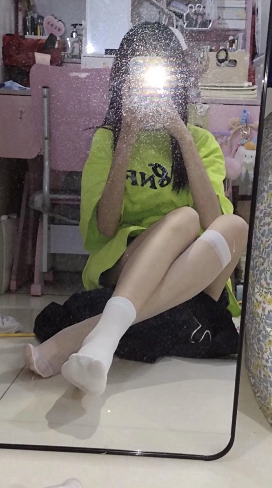 一位穿着绿色衬衫的女人在镜子前拍自拍。