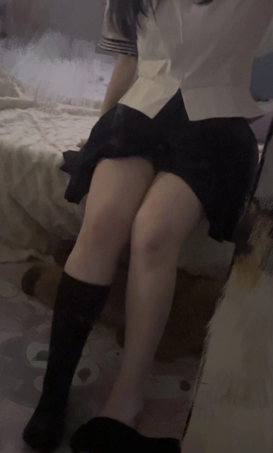 一位穿着白色衬衫和黑色衬衫的女人坐在床上。