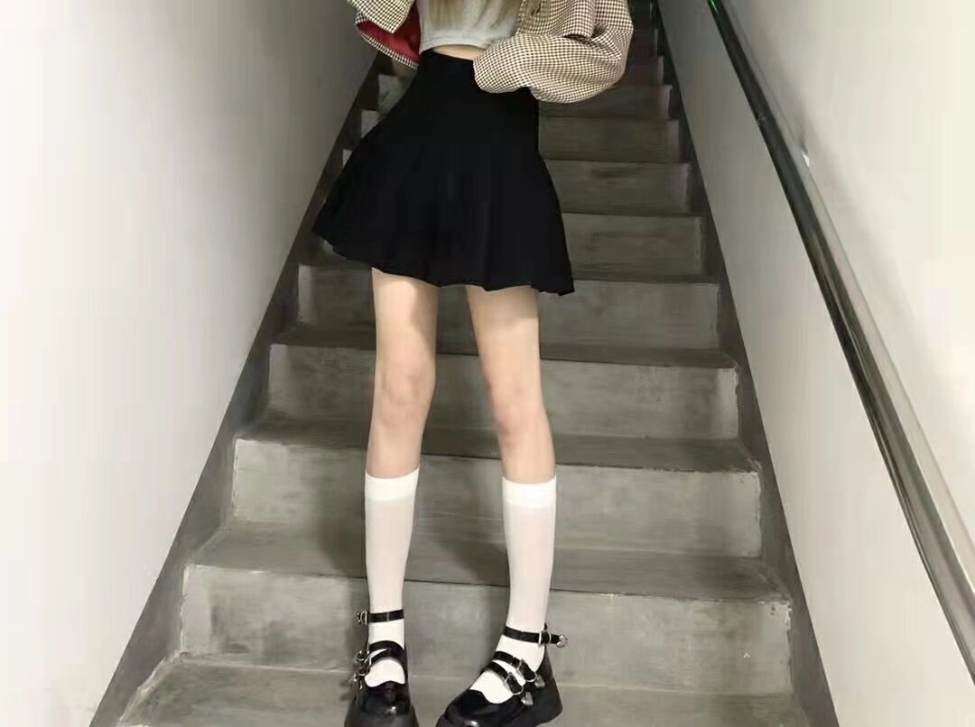 穿着黑色裙子和白色袜子的女人站在楼梯上。