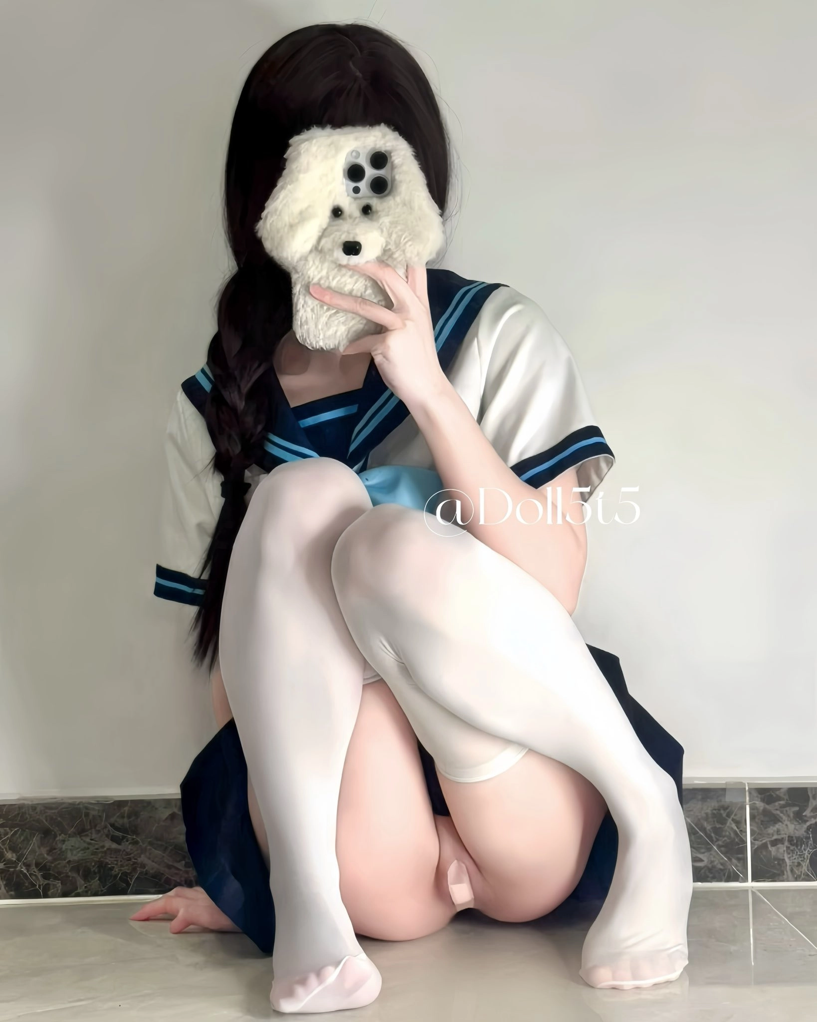 一位穿着白色衬衫和蓝色裙子的女孩抱着一只被填满的动物。