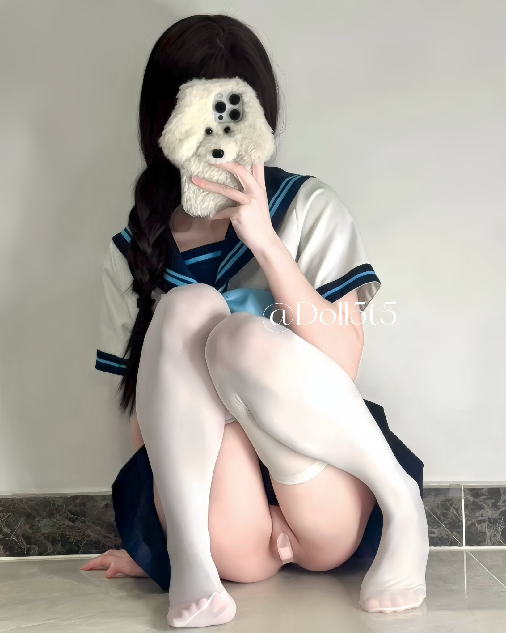 一位穿着白色衬衫和蓝色裙子的女孩抱着一只被填满的动物。