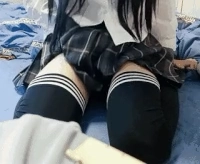 穿着白色衬衫和黑色衬衫的女孩坐在床上。