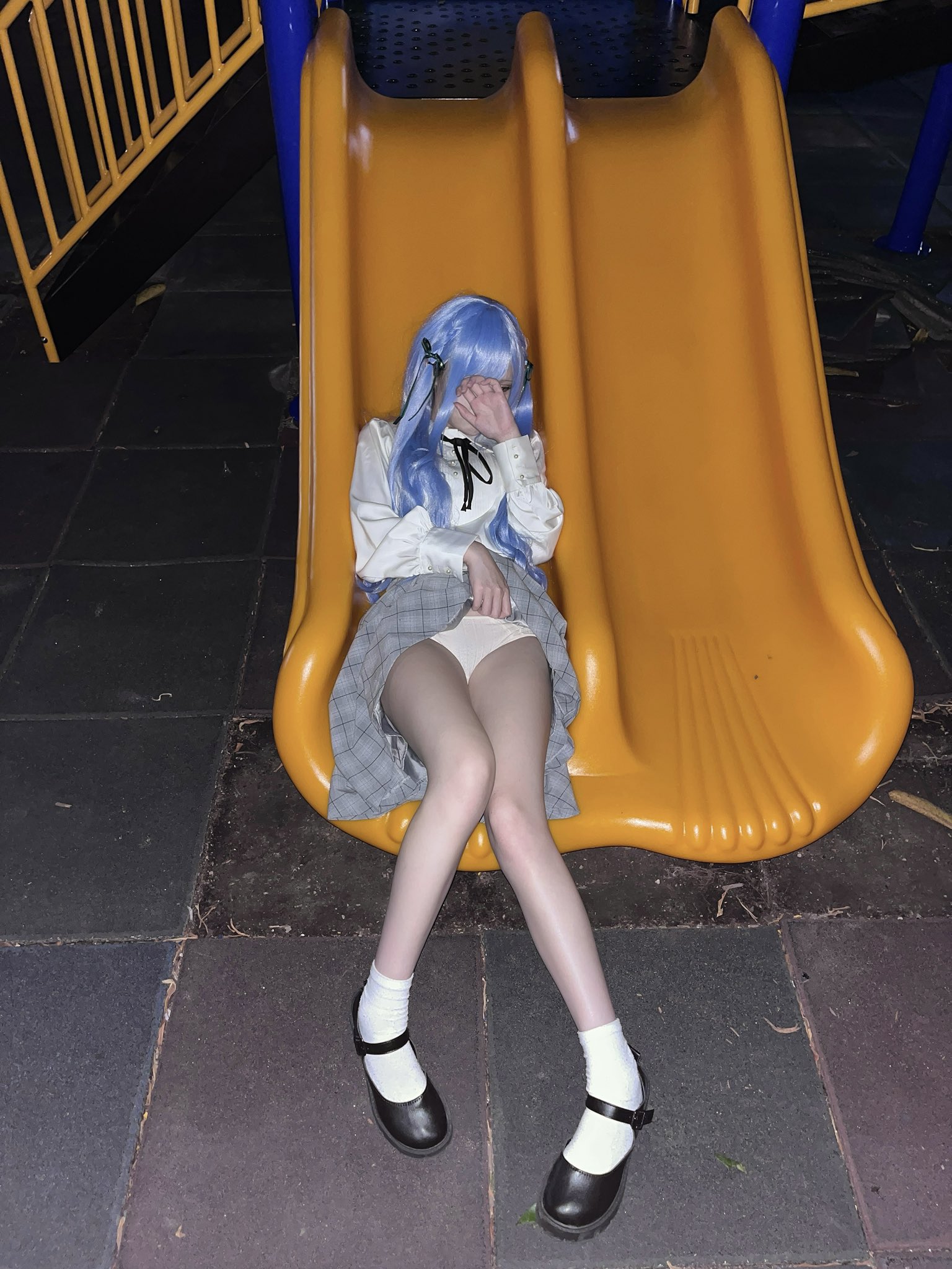 一位穿着蓝色裙子的女孩坐在滑板上。