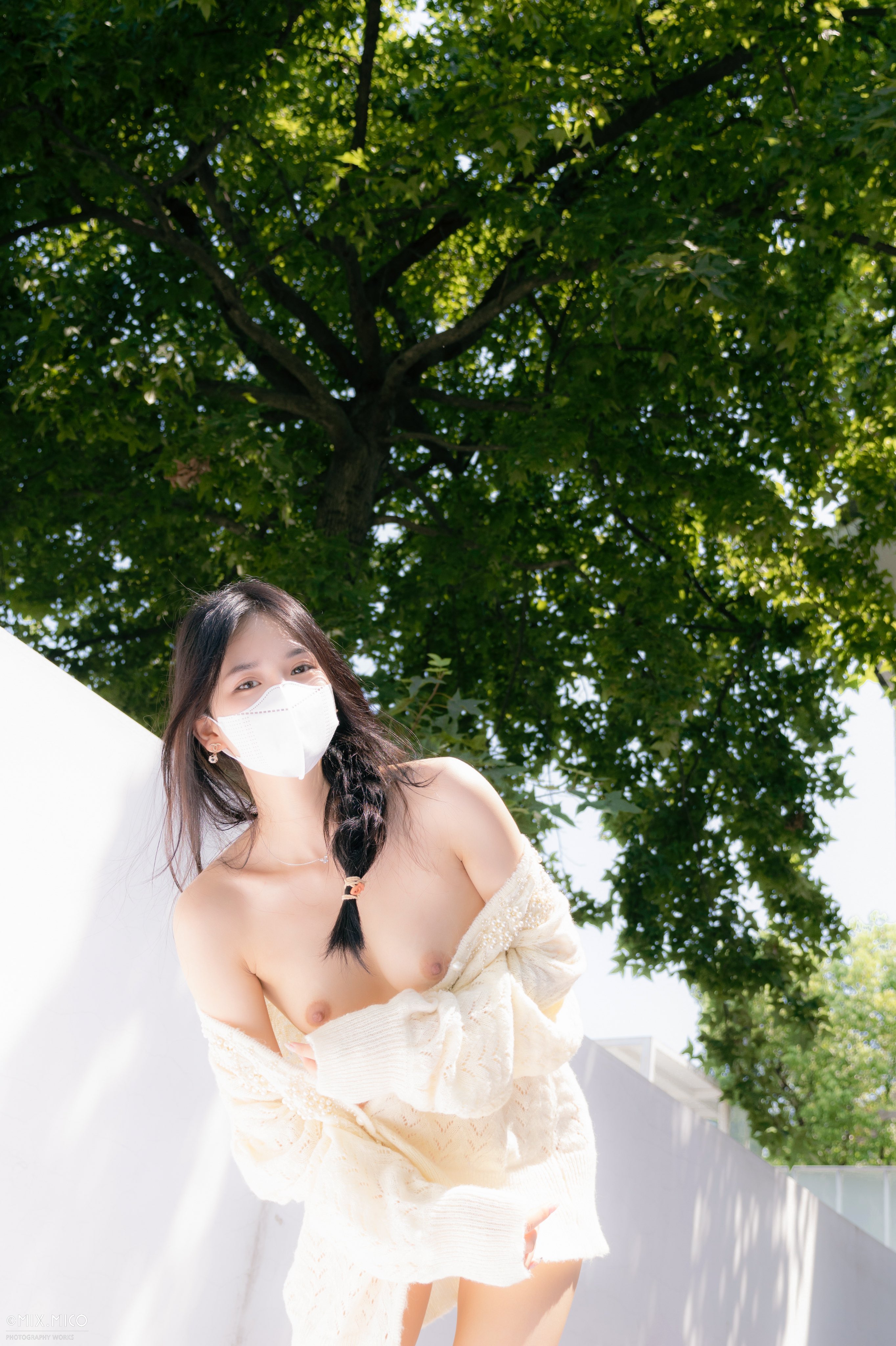 戴着面具的女人站在一棵树前。