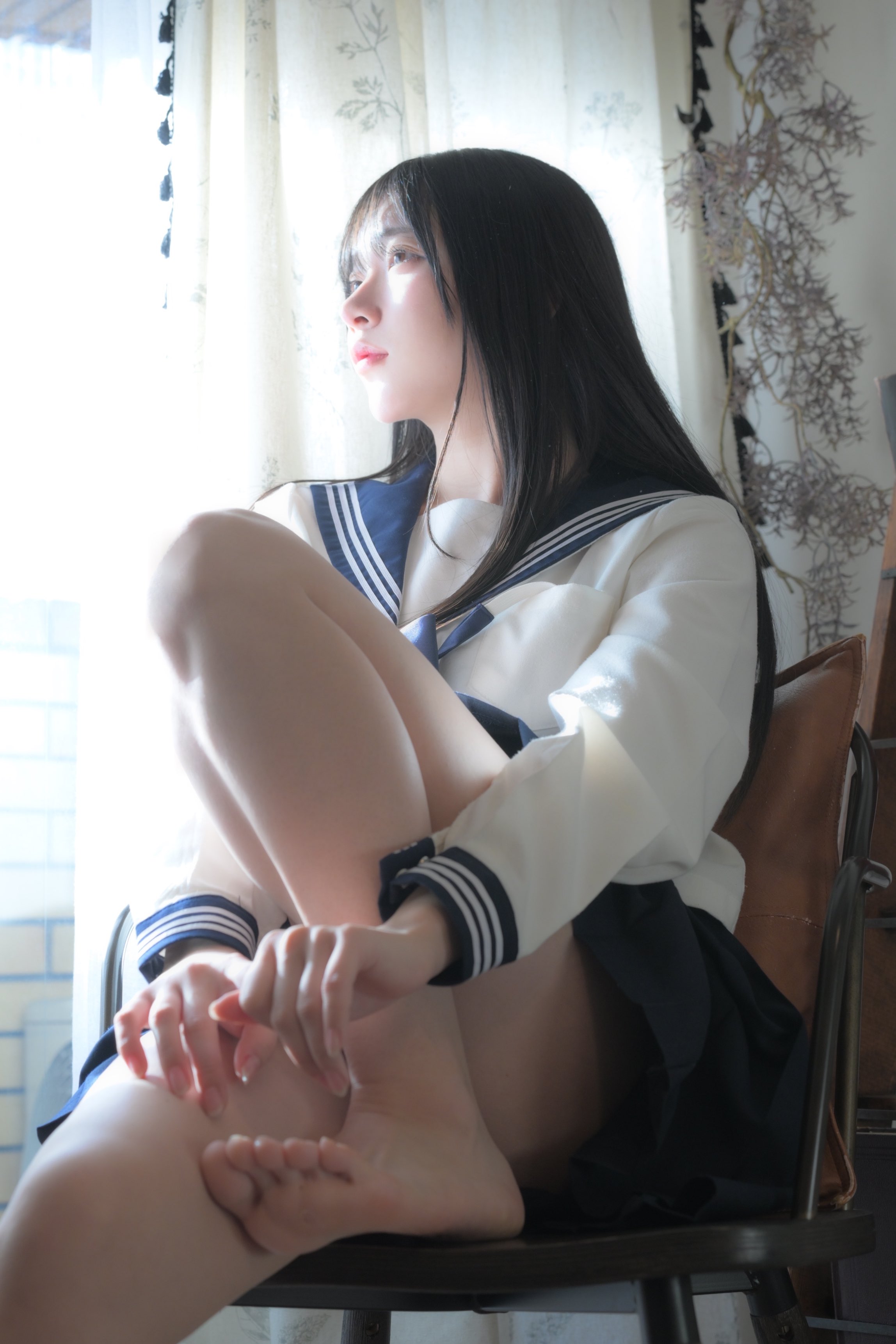 穿着蓝色和白色的水手服的女人坐在椅子上。