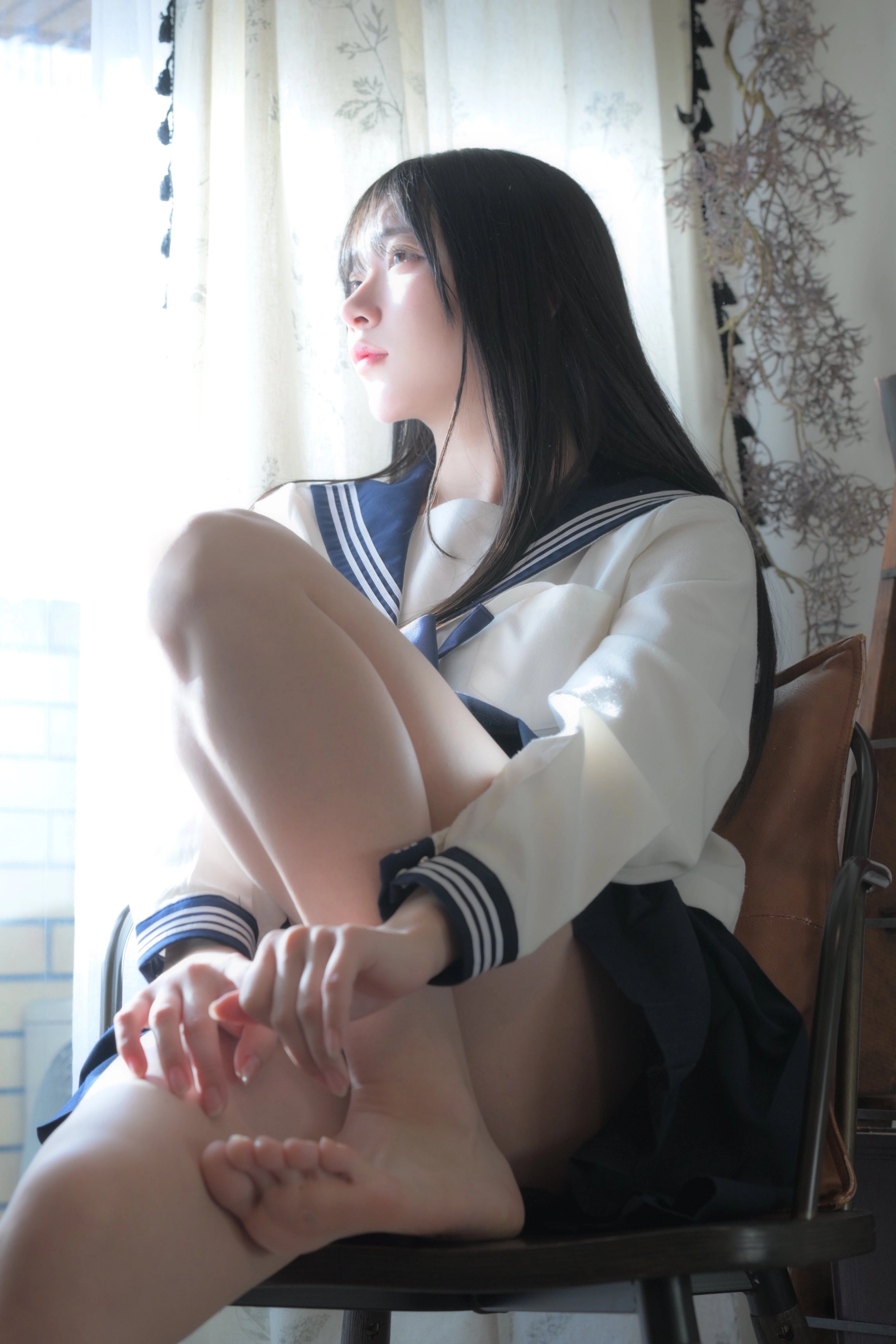 穿着蓝色和白色的水手服的女人坐在椅子上。