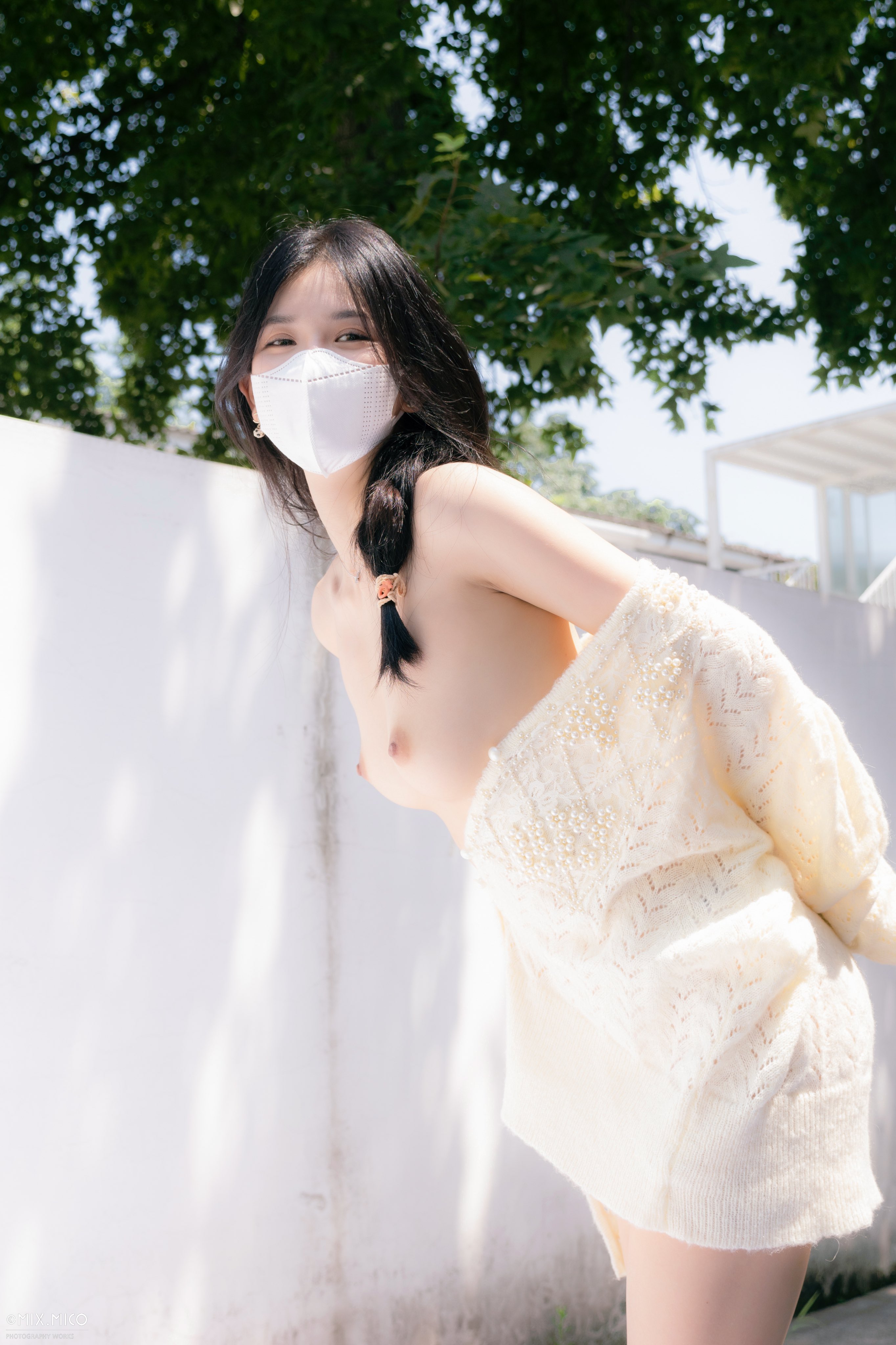 戴着面具的女人站在一棵树前。