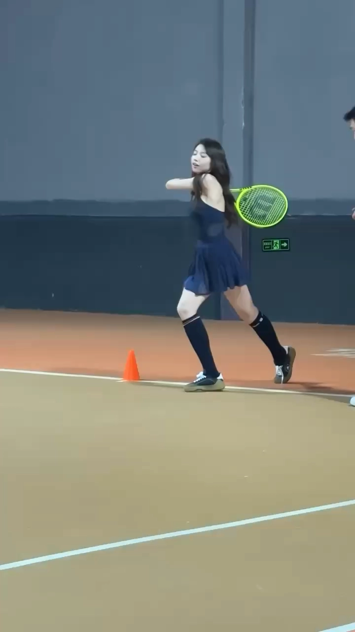 一位穿着蓝色衣服的女人在球上跳一根网球球。