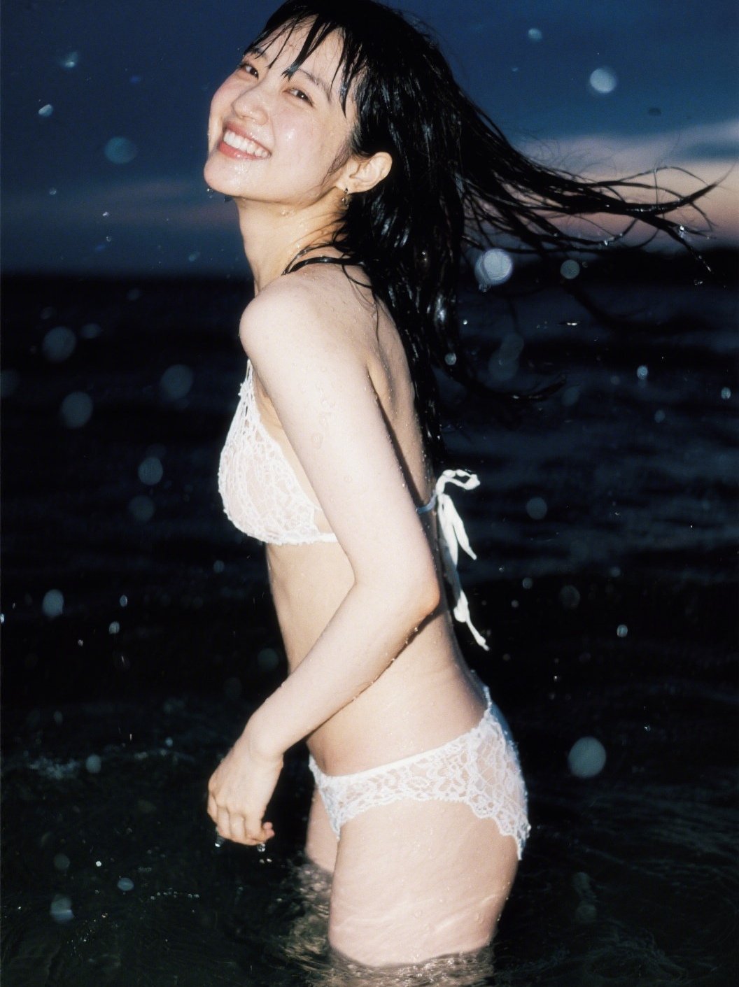 穿着白色比基尼顶部和白色袖子底部的女人正在微笑,并为一张照片露面。