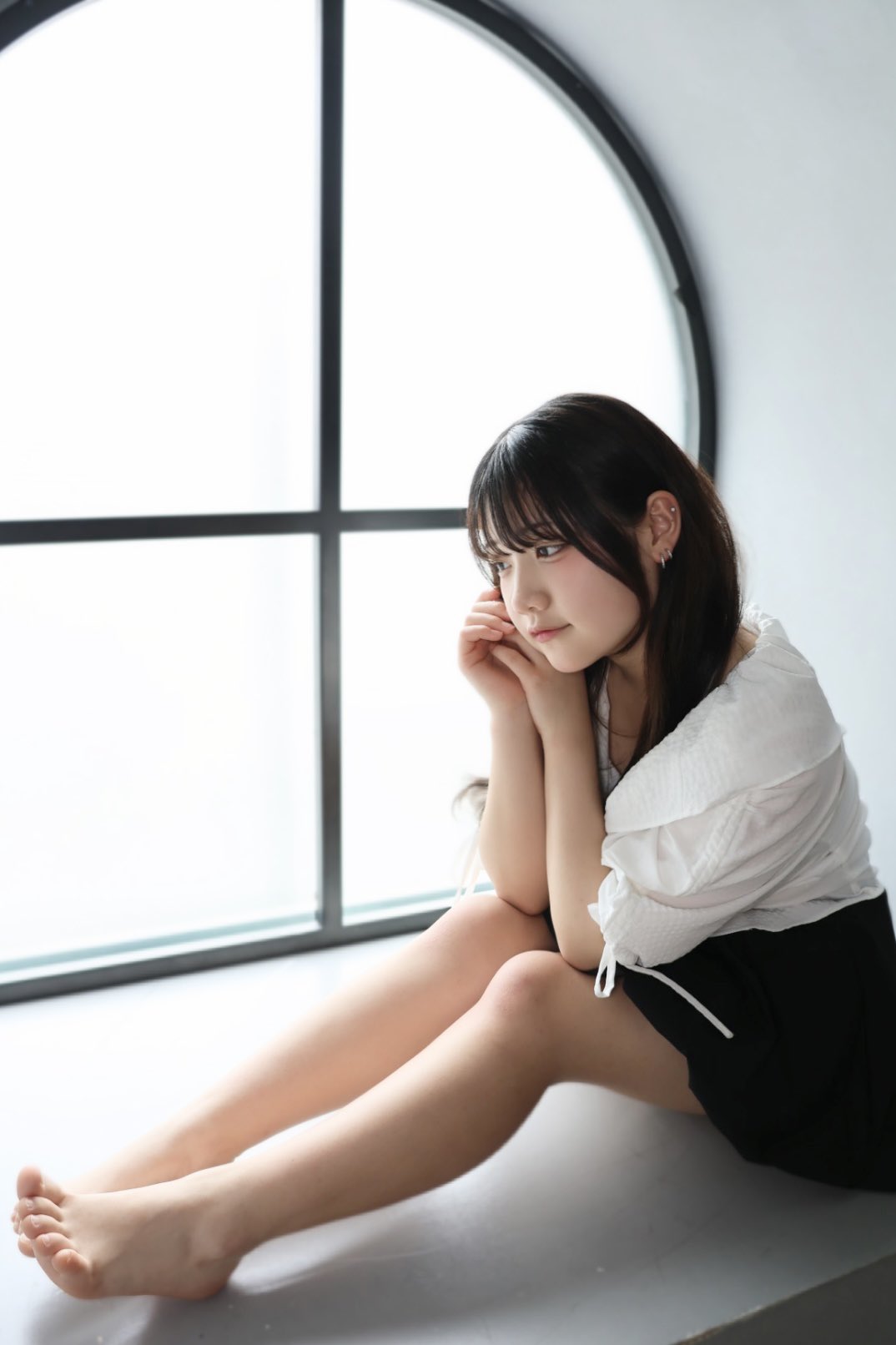 长头发和白衬衫的女人坐在窗前。