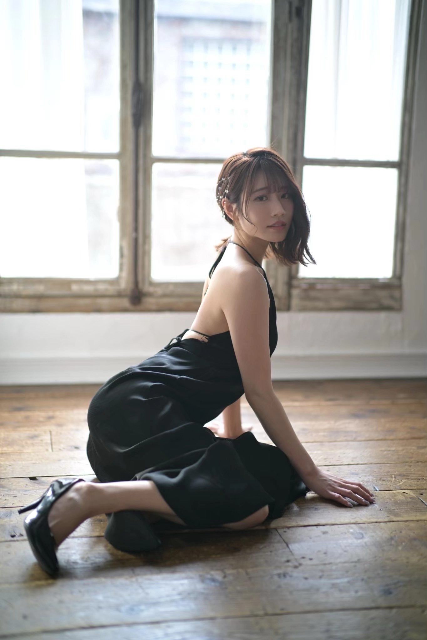 穿着黑色衣服的女人坐在木地板上。