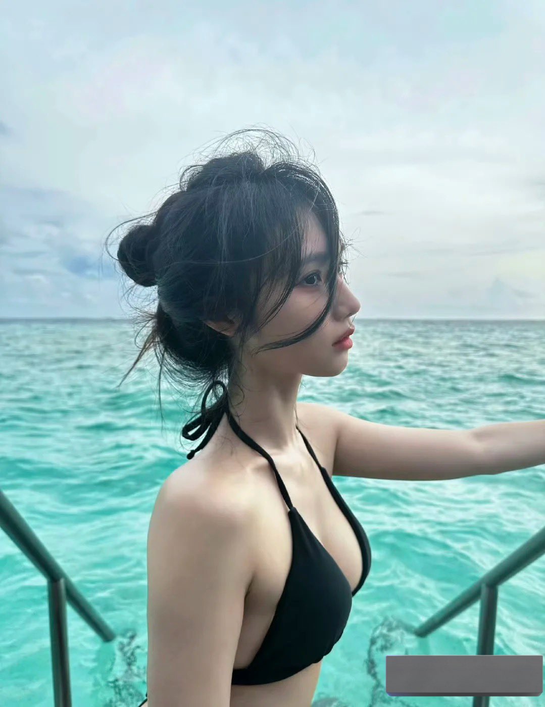 一位穿黑色比基尼的女人站在一艘船上。