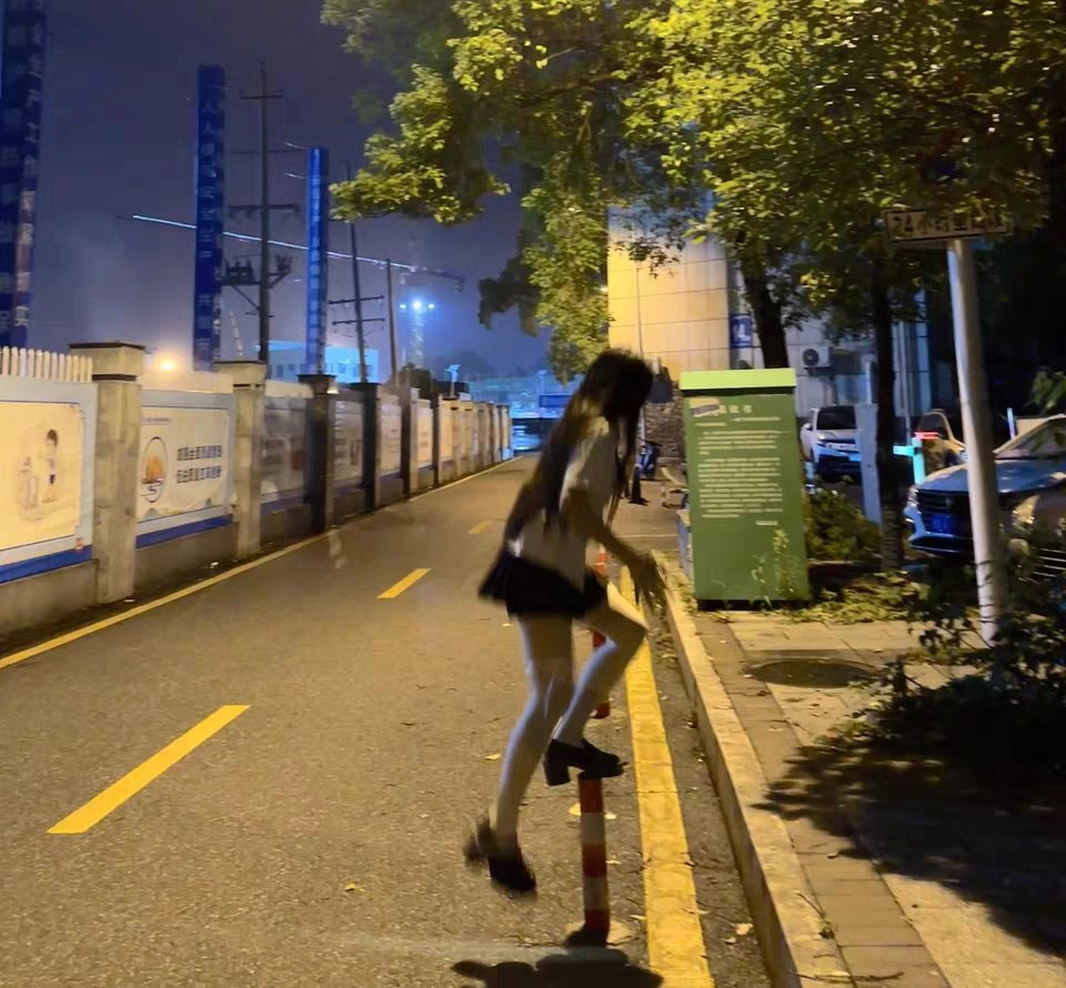 穿着白色衬衫和黑色裙子的女人跳过一个红色极点。