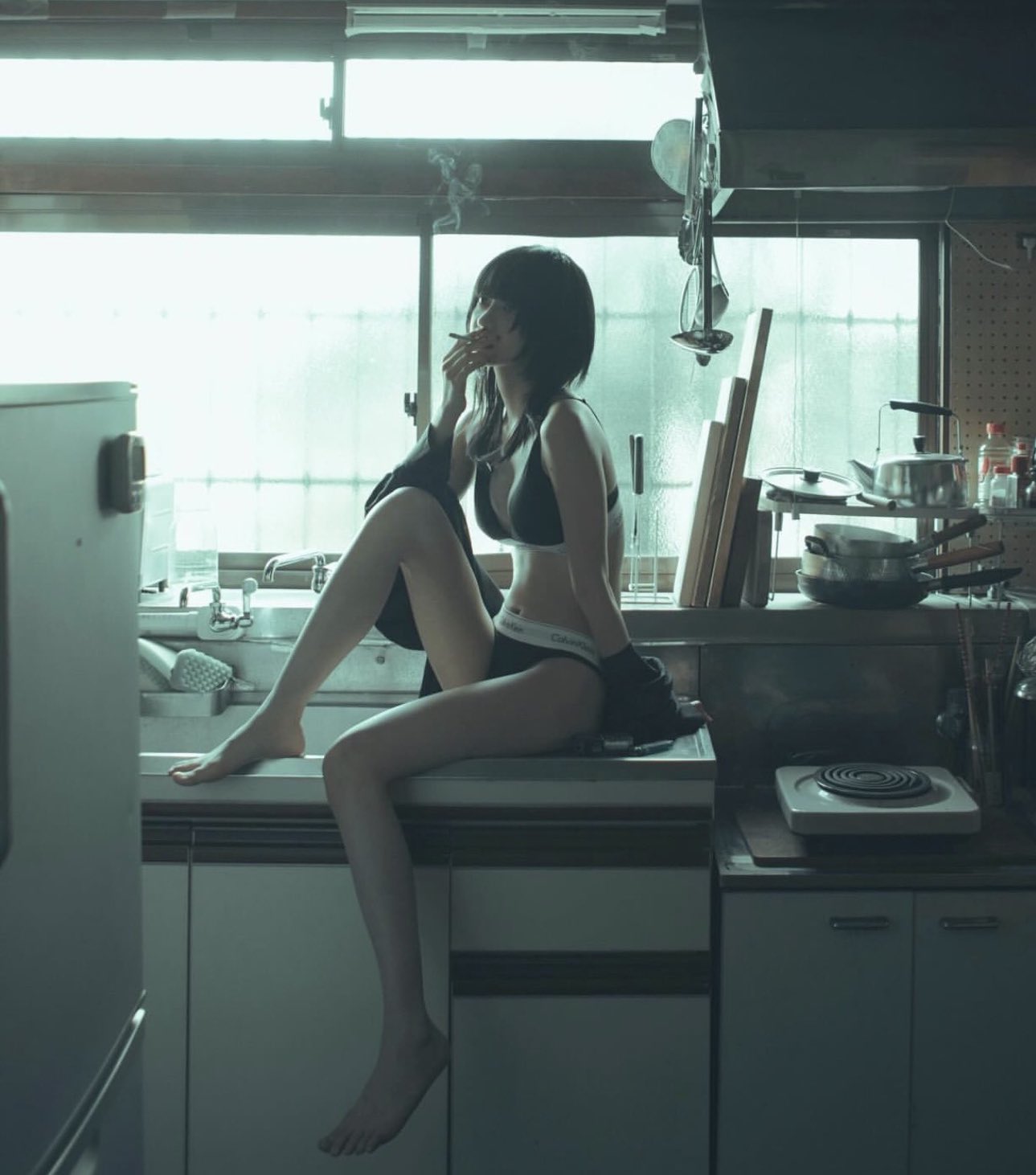 女人在厨房柜子上坐着抽一支烟。